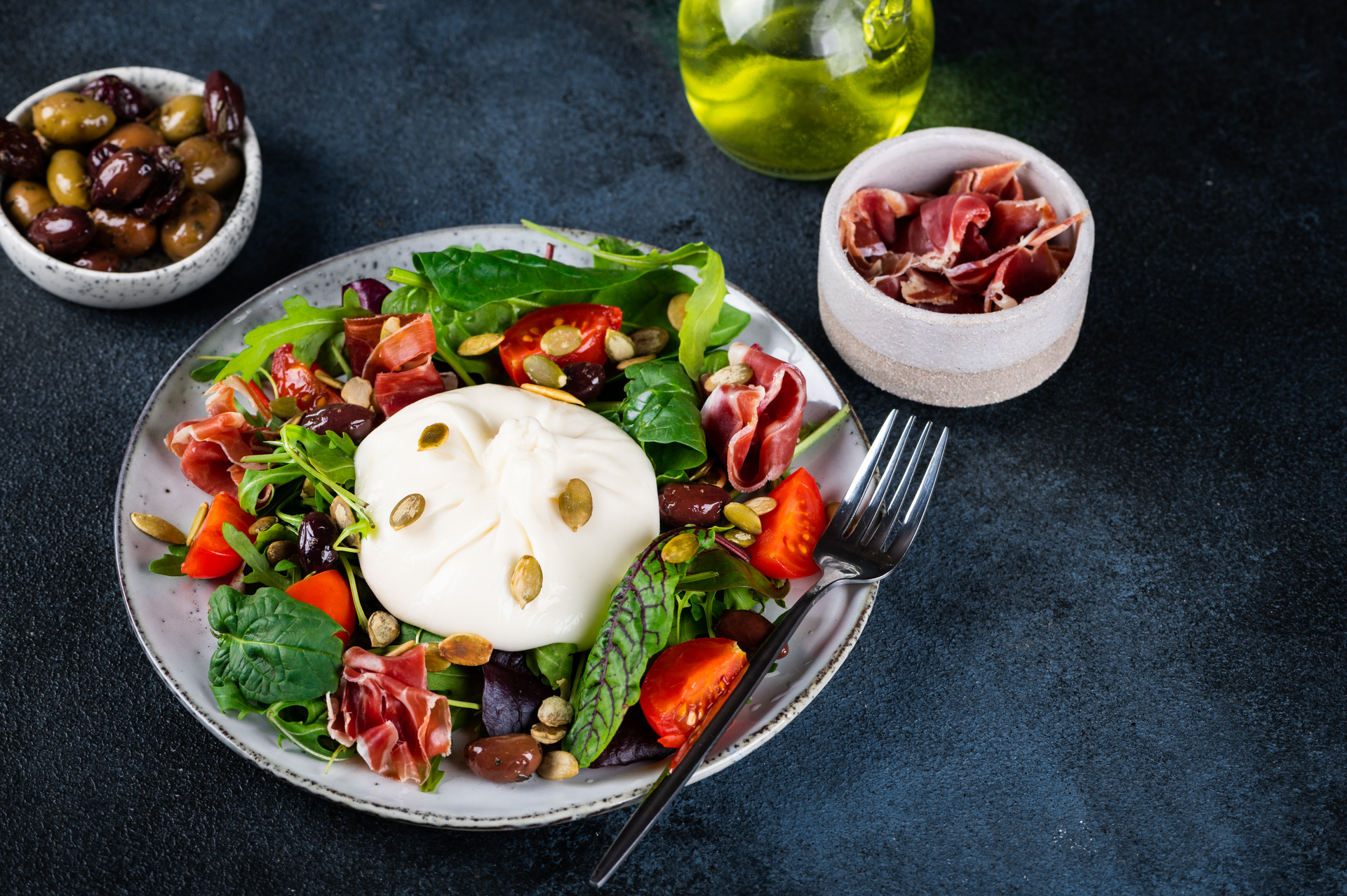 Overhead flat-lay of all ingredients for Italian Herb-Infused Burrata Salad with Balsamic Reduction laid out on a kitchen surface.
