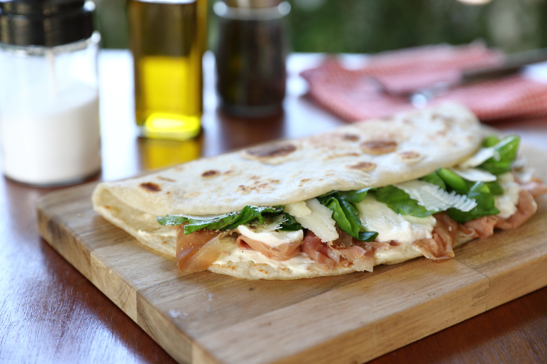Overhead flat-lay of all ingredients for Italian Piadina with Prosciutto and Arugula laid out on a kitchen surface.