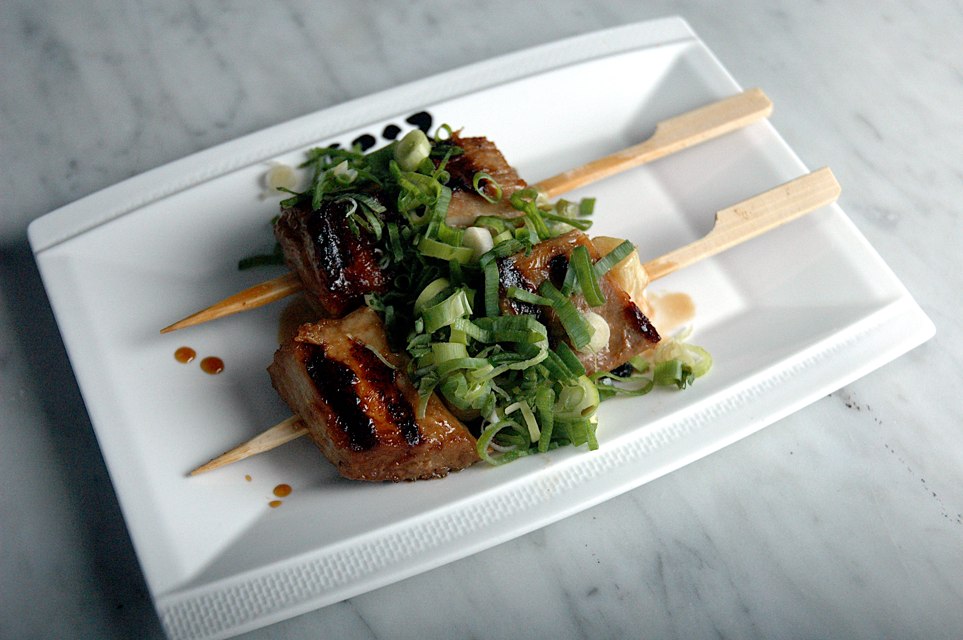 Overhead flat-lay of all ingredients for Japanese Yuzu Kosho Chicken Skewers with Grilled Shishito Peppers laid out on a kitchen surface.