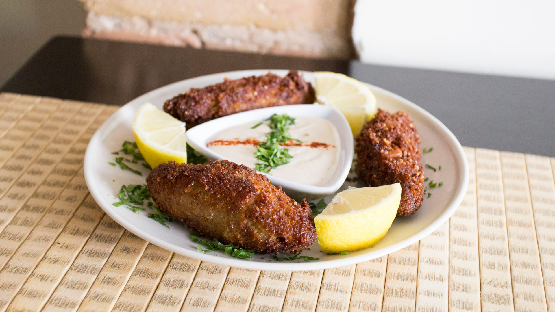 Overhead flat-lay of all ingredients for Kibbeh Bil Sanieh with Tahini Sauce laid out on a kitchen surface.