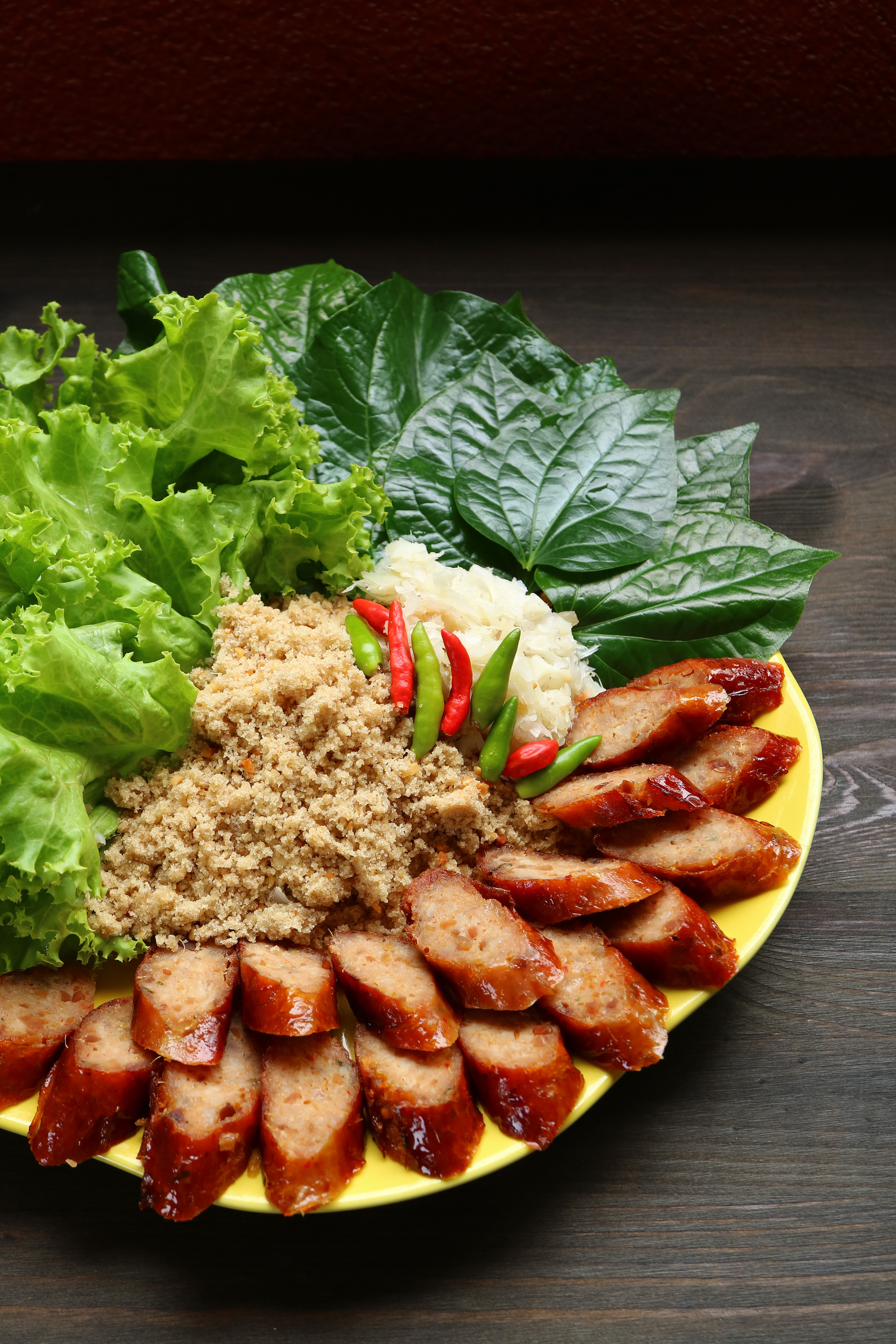 Overhead flat-lay of all ingredients for Laotian Lemongrass Pork Sausages with Green Papaya Salad laid out on a kitchen surface.