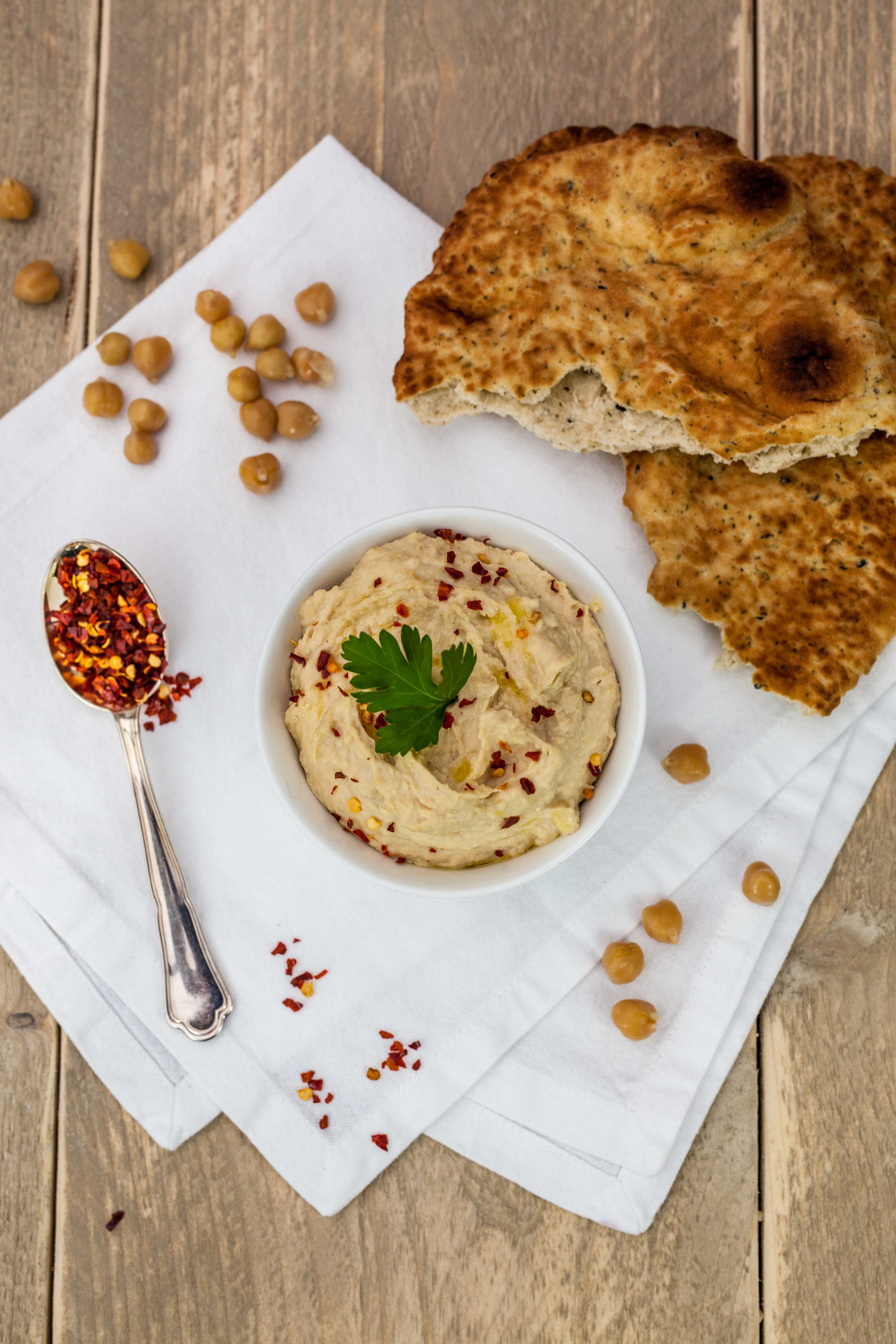 Overhead flat-lay of all ingredients for Lebanese Fattet Hummus with Pita and Pine Nuts laid out on a kitchen surface.