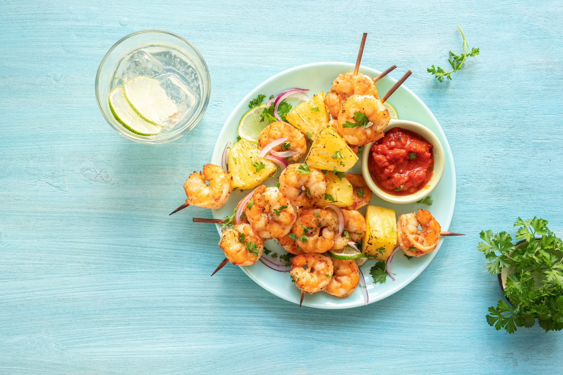 Overhead flat-lay of all ingredients for Malaysian Turmeric Coconut Shrimp Skewers with Citrus Dip laid out on a kitchen surface.
