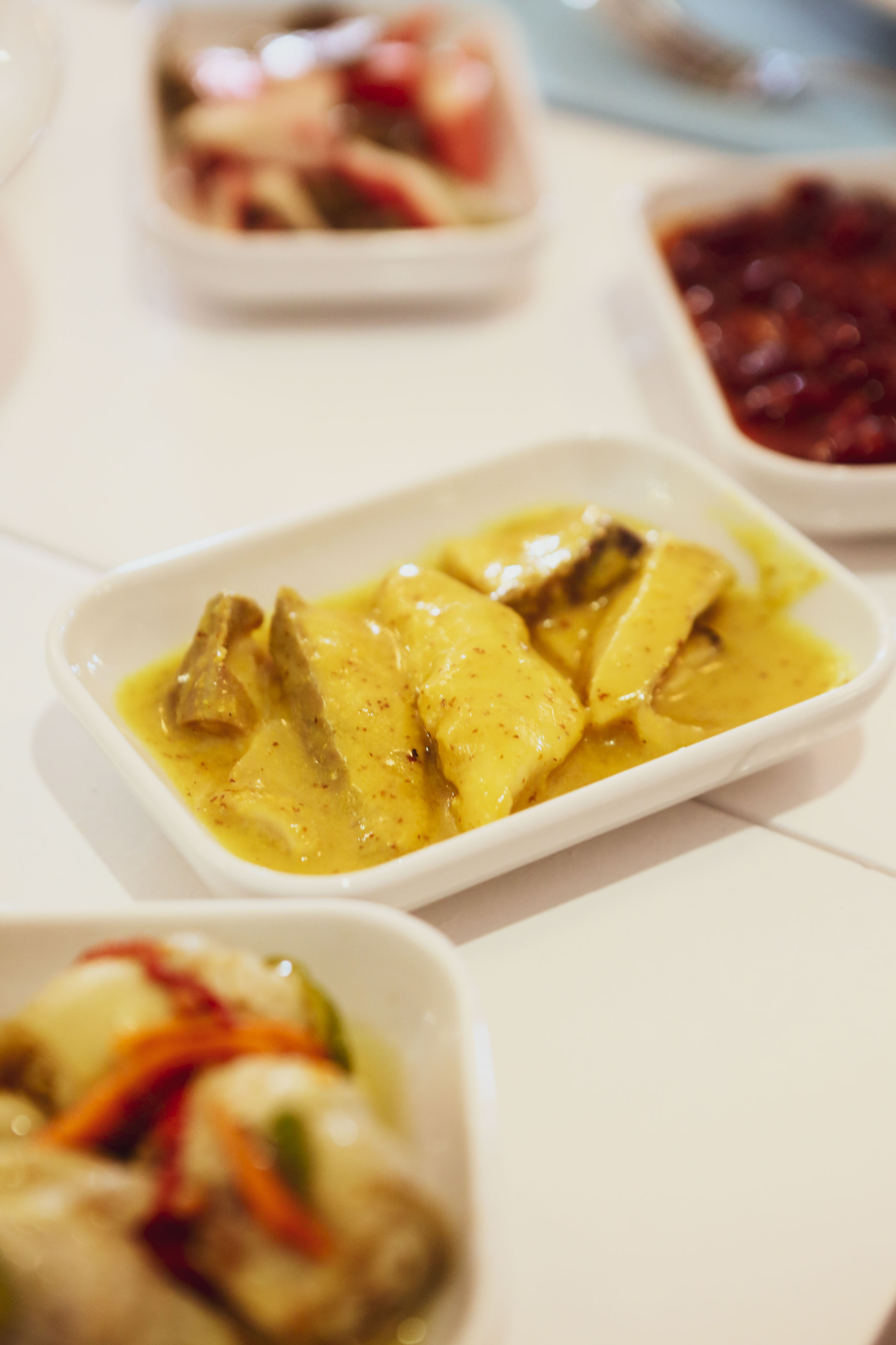 Overhead flat-lay of all ingredients for Mauritian Three Curry Saunds with Fermented Mango Chutney laid out on a kitchen surface.