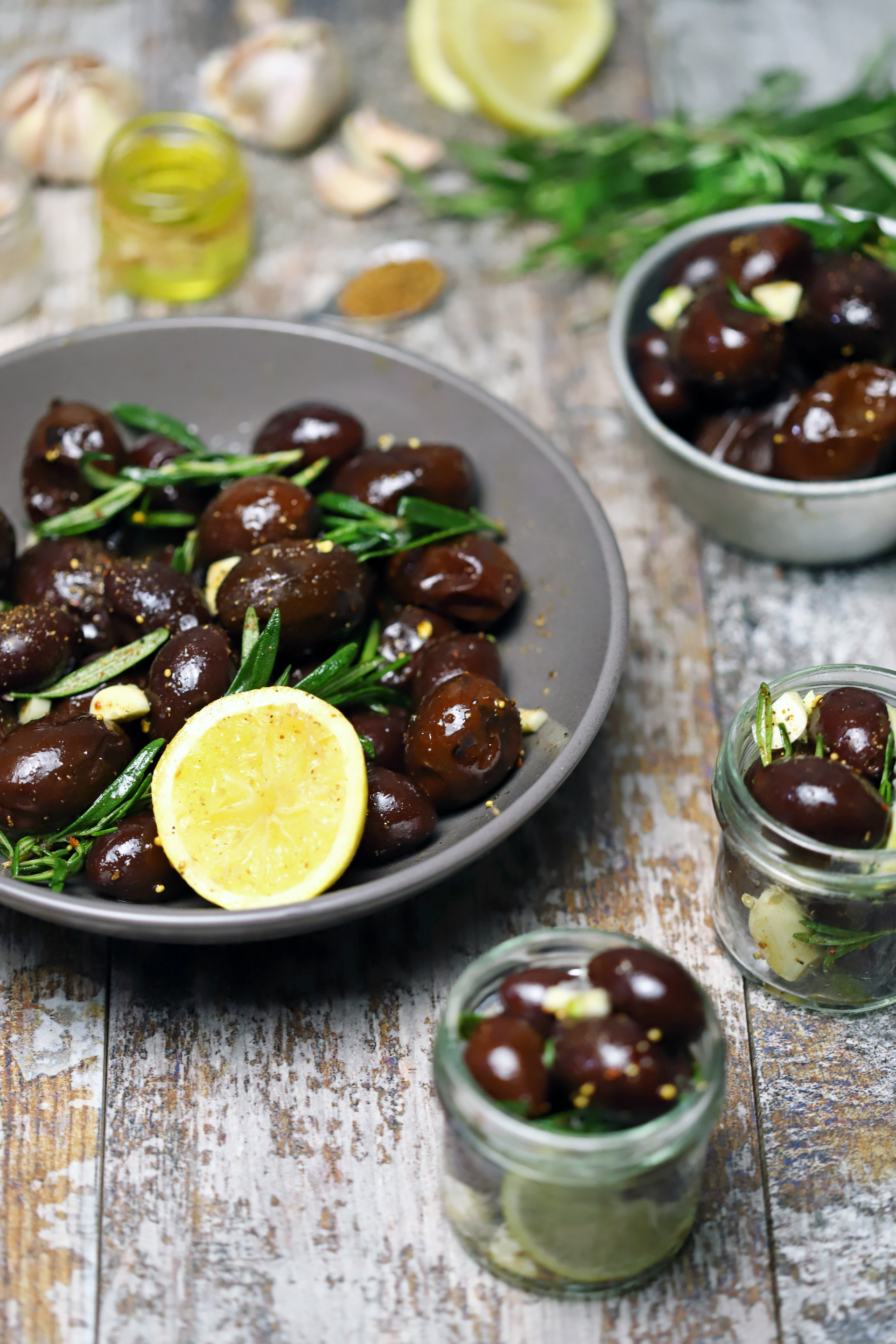 Overhead flat-lay of all ingredients for Mediterranean Herb-Roasted Olives laid out on a kitchen surface.