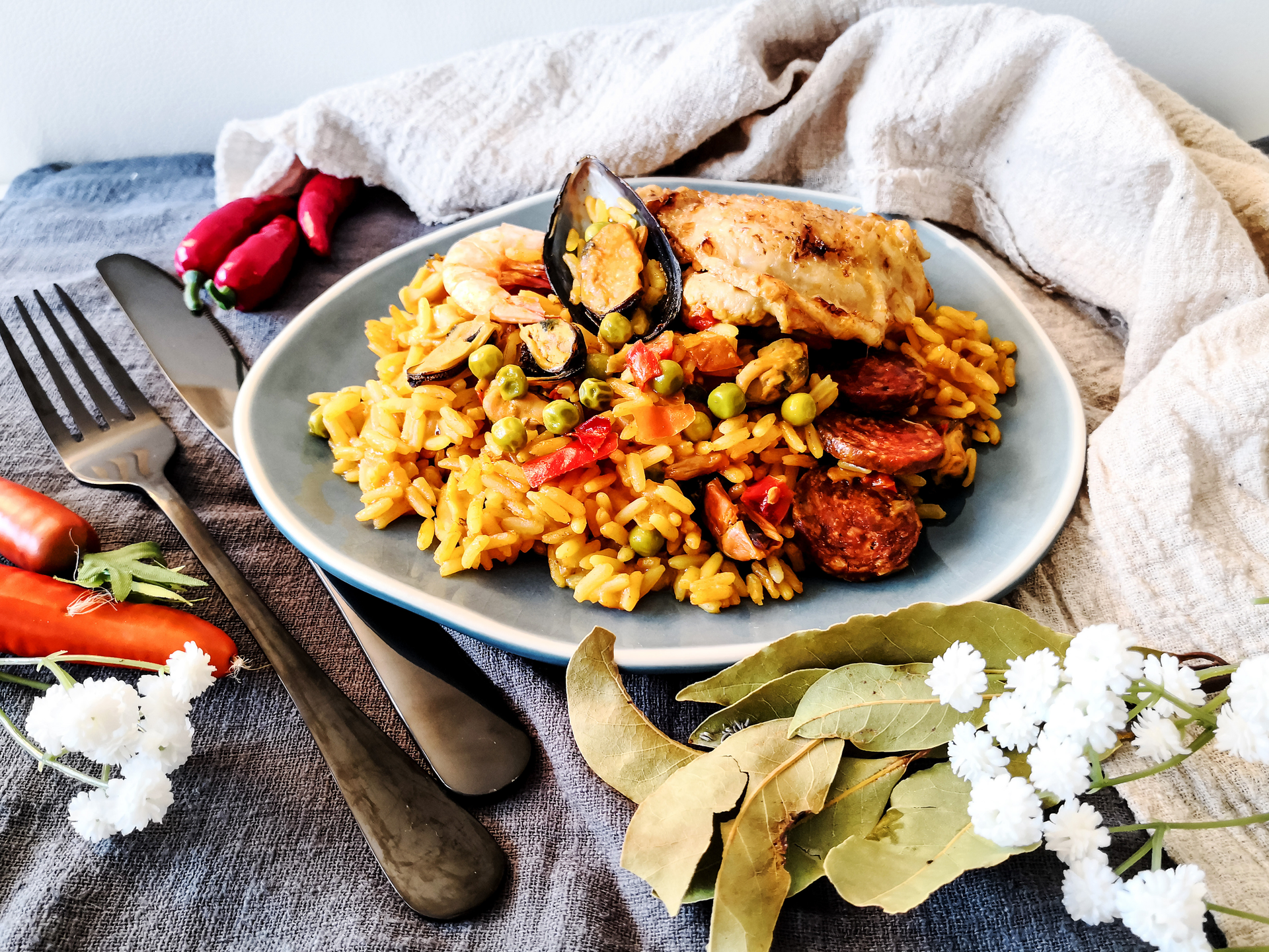 Overhead flat-lay of all ingredients for Mediterranean Saffron Chicken Paella with Artichokes laid out on a kitchen surface.