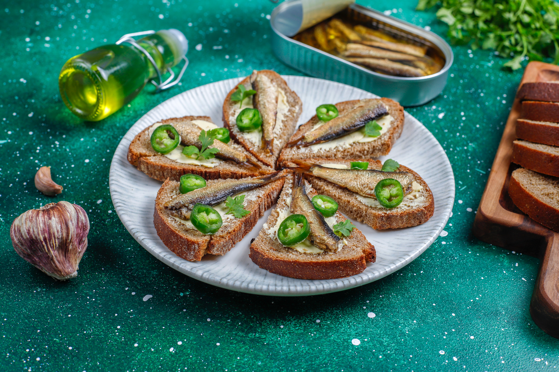 Overhead flat-lay of all ingredients for Mediterranean Sardine Crostini with Lemon Capers laid out on a kitchen surface.