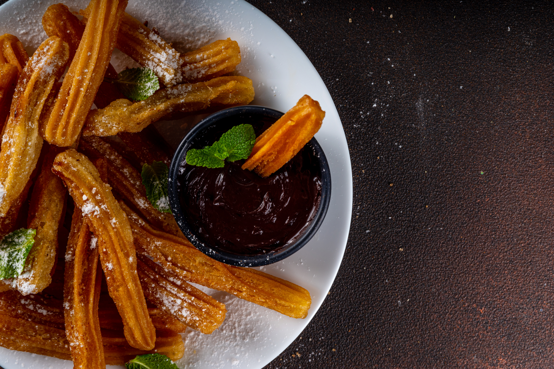 Overhead flat-lay of all ingredients for Mexican Chocolate-Infused Churros with Chili and Cinnamon Glaze laid out on a kitchen surface.