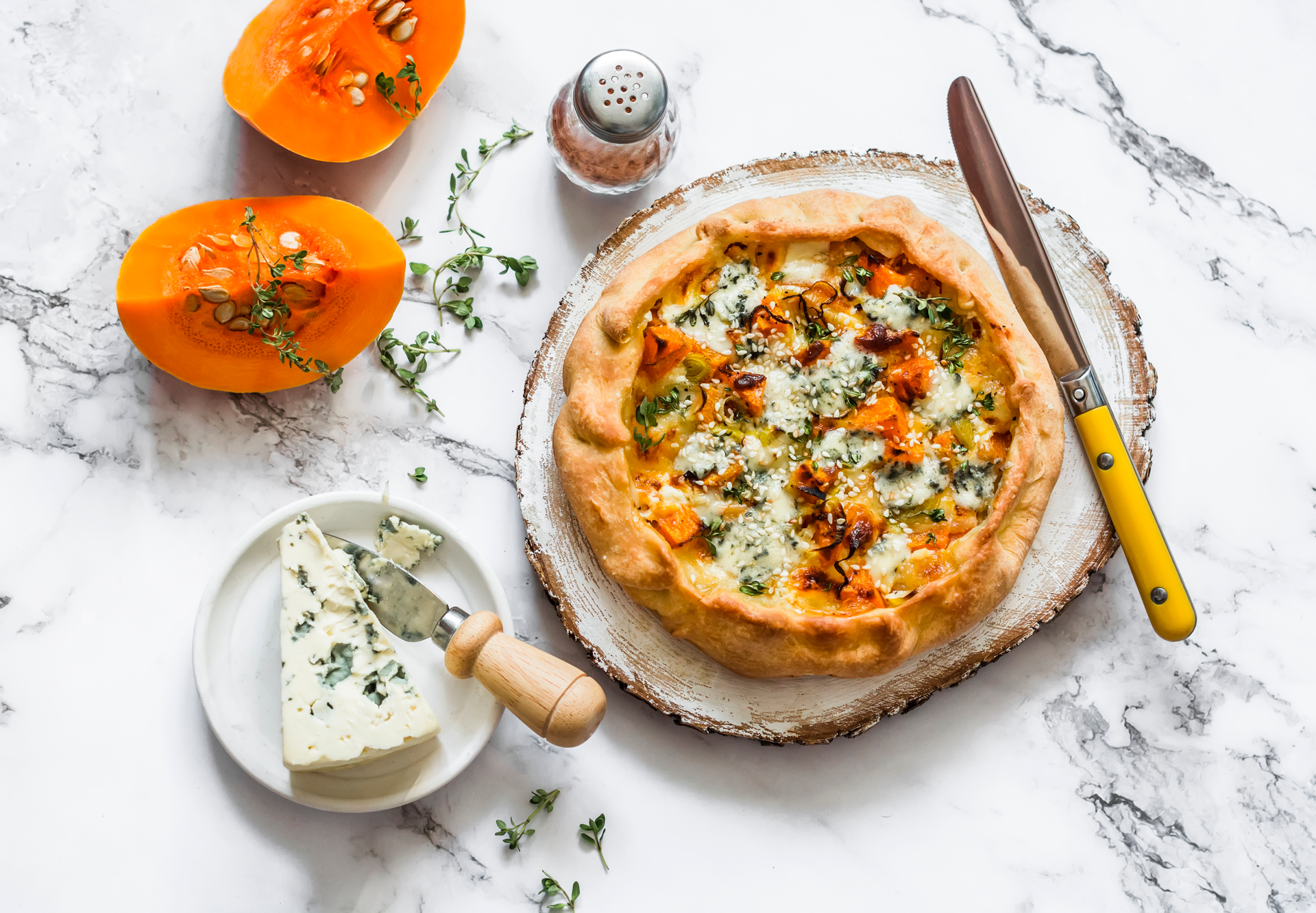 Overhead flat-lay of all ingredients for Moroccan Pumpkin and Harissa Flatbread with Mint Yogurt laid out on a kitchen surface.