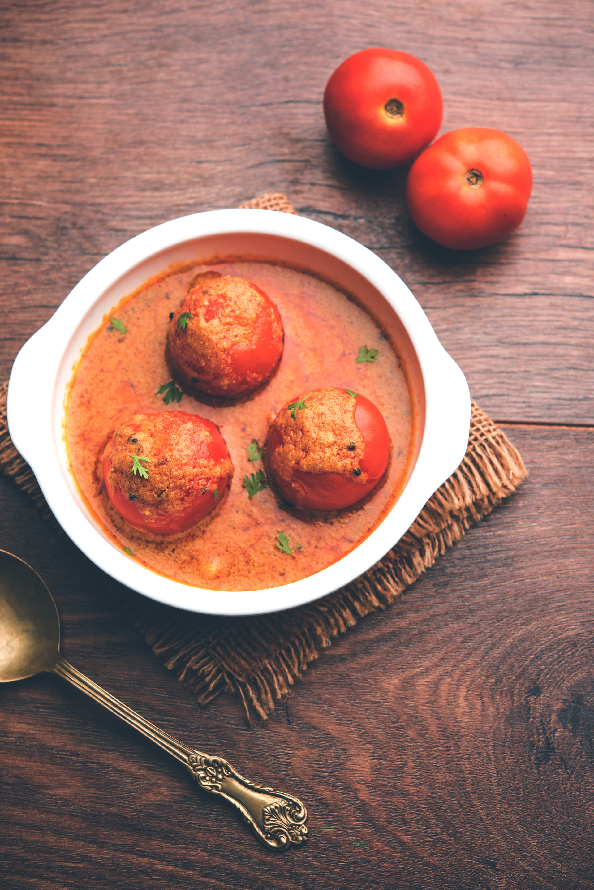 Overhead flat-lay of all ingredients for Nargisi Kofta with Rich Tomato Gravy laid out on a kitchen surface.