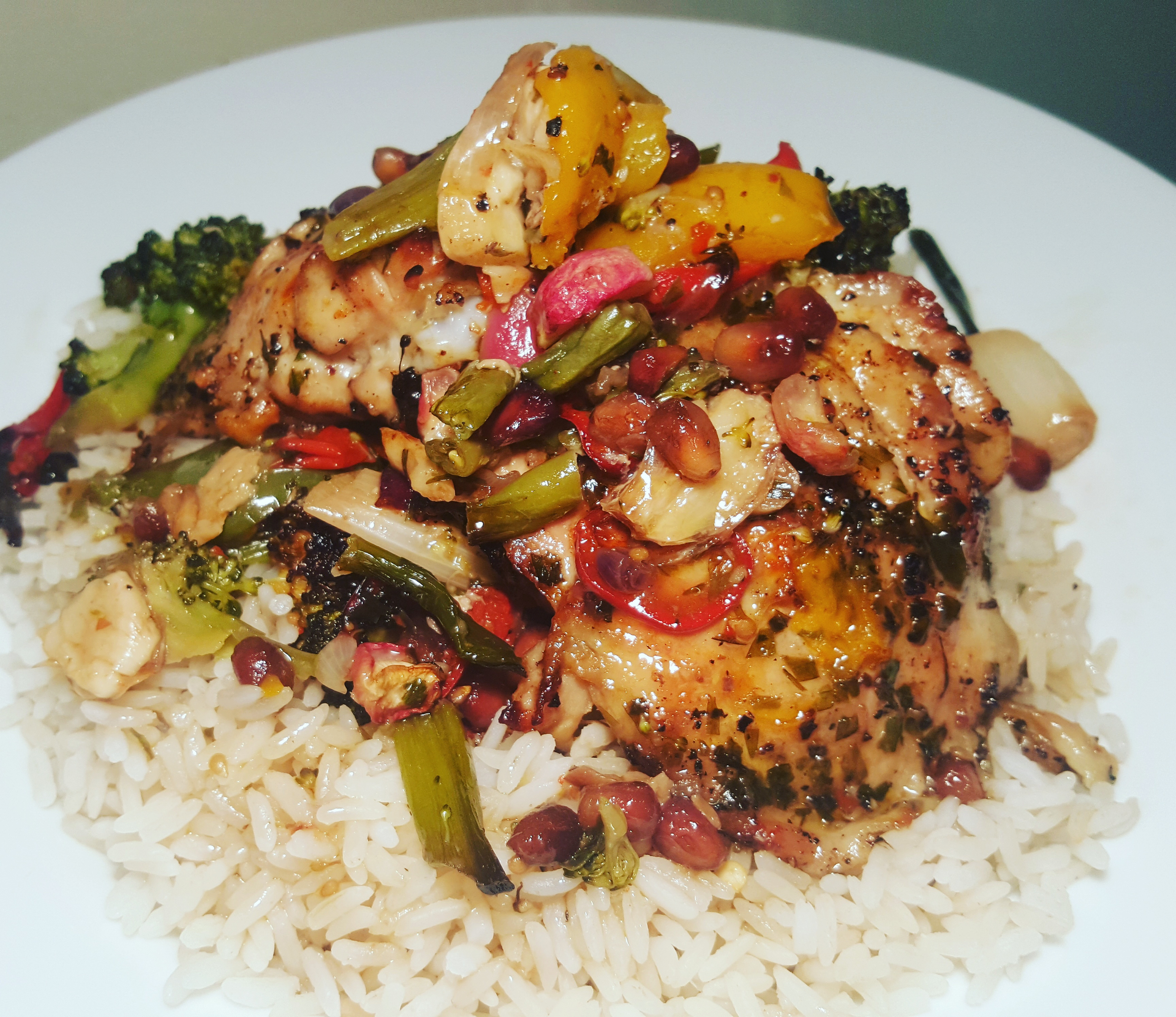 Overhead flat-lay of all ingredients for Nigerian Jollof Orzo with Bell Peppers and Chicken laid out on a kitchen surface.