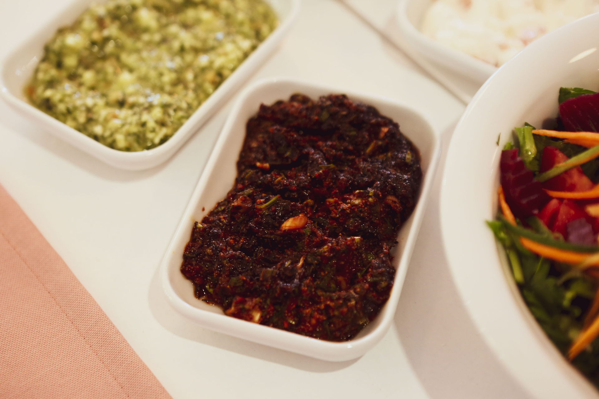 Overhead flat-lay of all ingredients for Nut-Crusted Tanzanian Nyama Choma with Spicy Bean Relish laid out on a kitchen surface.