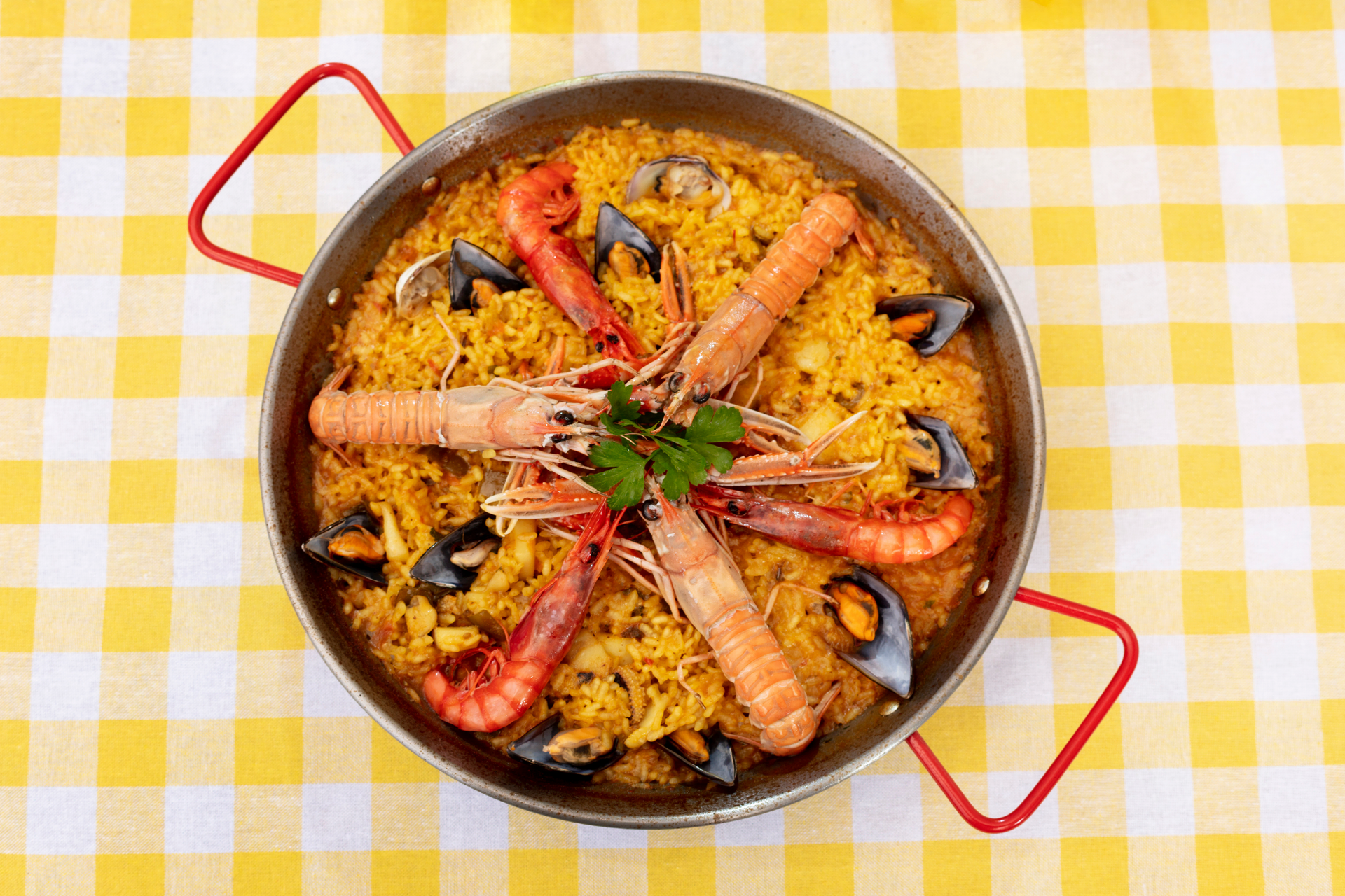 Overhead flat-lay of all ingredients for Paella Valenciana laid out on a kitchen surface.
