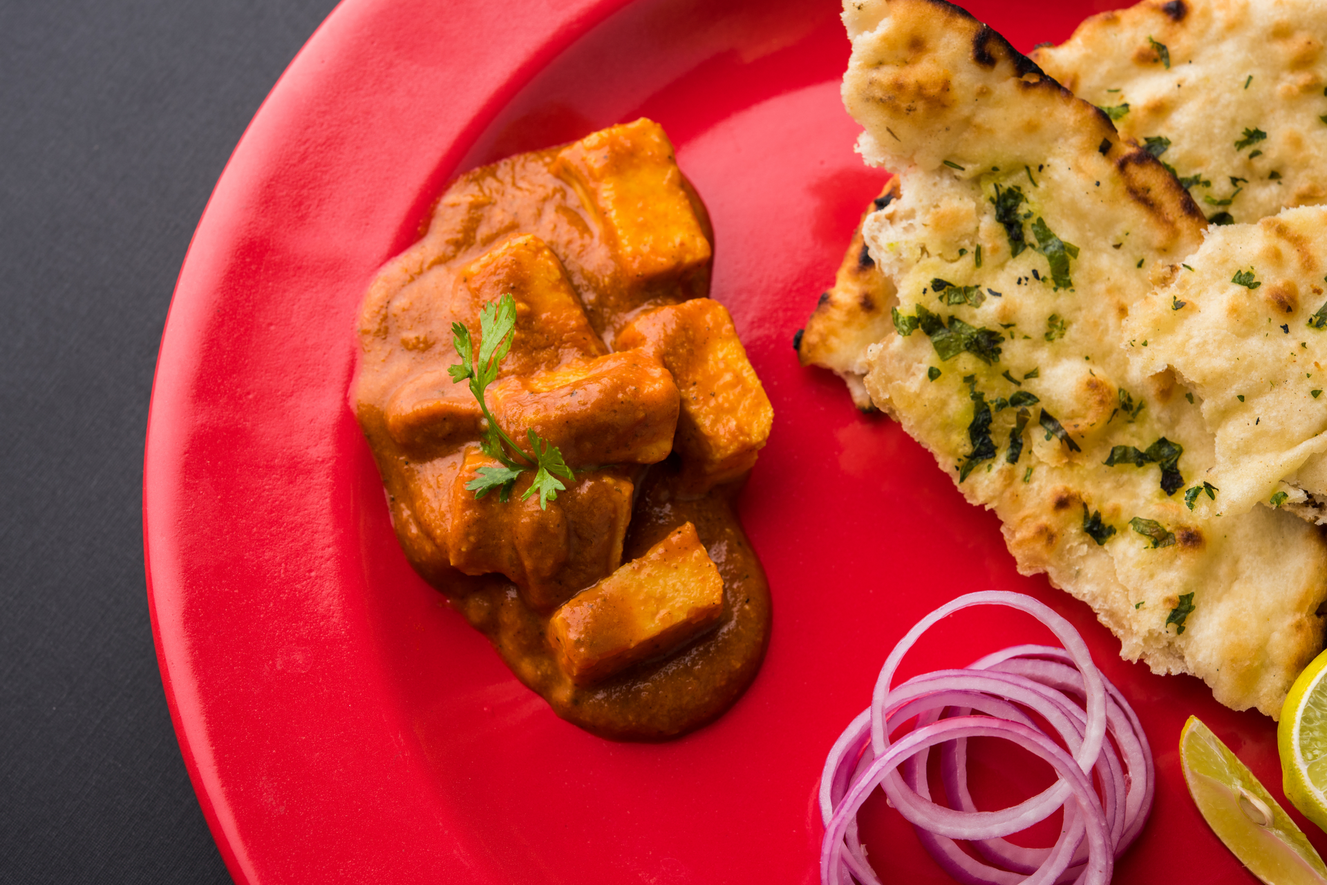 Overhead flat-lay of all ingredients for Paneer Butter Masala with Naan laid out on a kitchen surface.