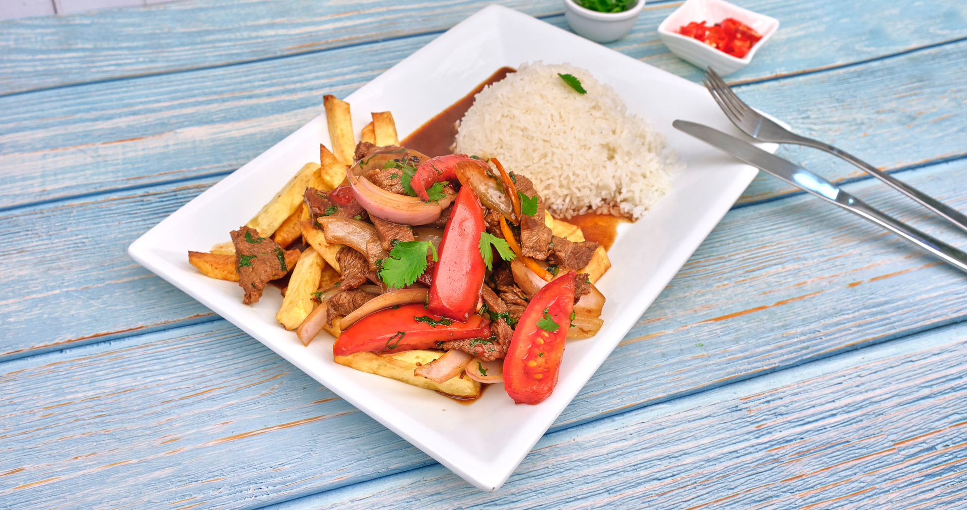 Overhead flat-lay of all ingredients for Peruvian Lomo Saltado laid out on a kitchen surface.