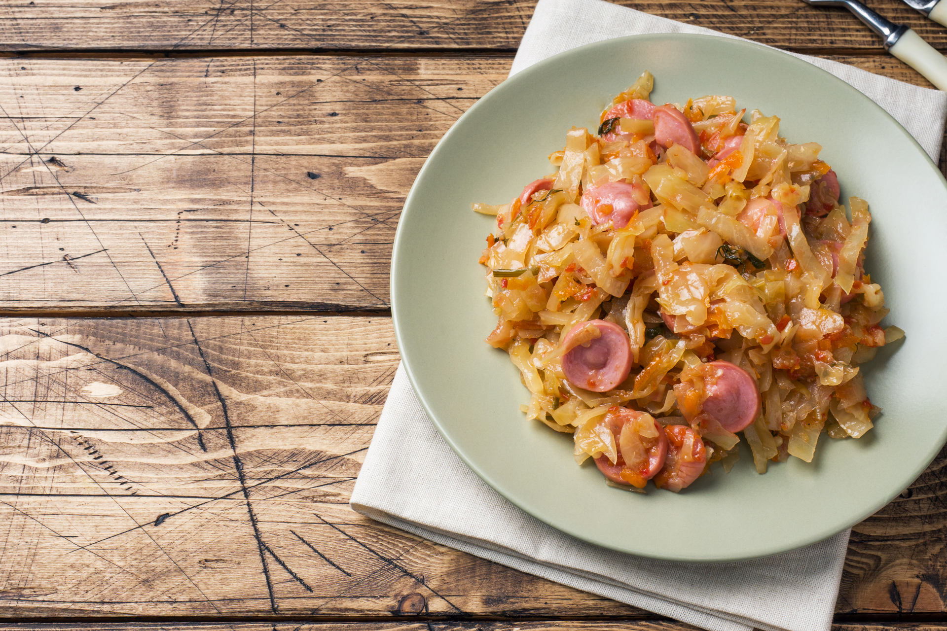 Overhead flat-lay of all ingredients for Polish Bigos with Sauerkraut and Sausage laid out on a kitchen surface.