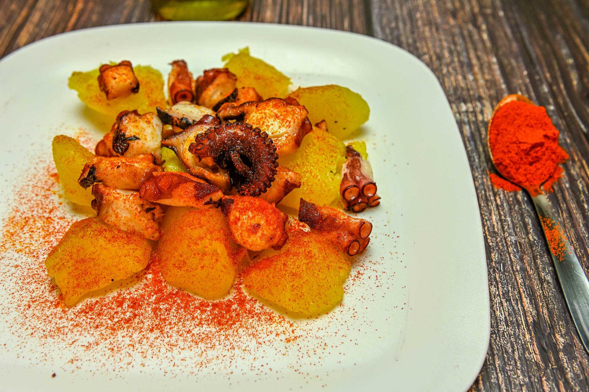 Overhead flat-lay of all ingredients for Pulpo a la Gallega with Potatoes and Paprika laid out on a kitchen surface.