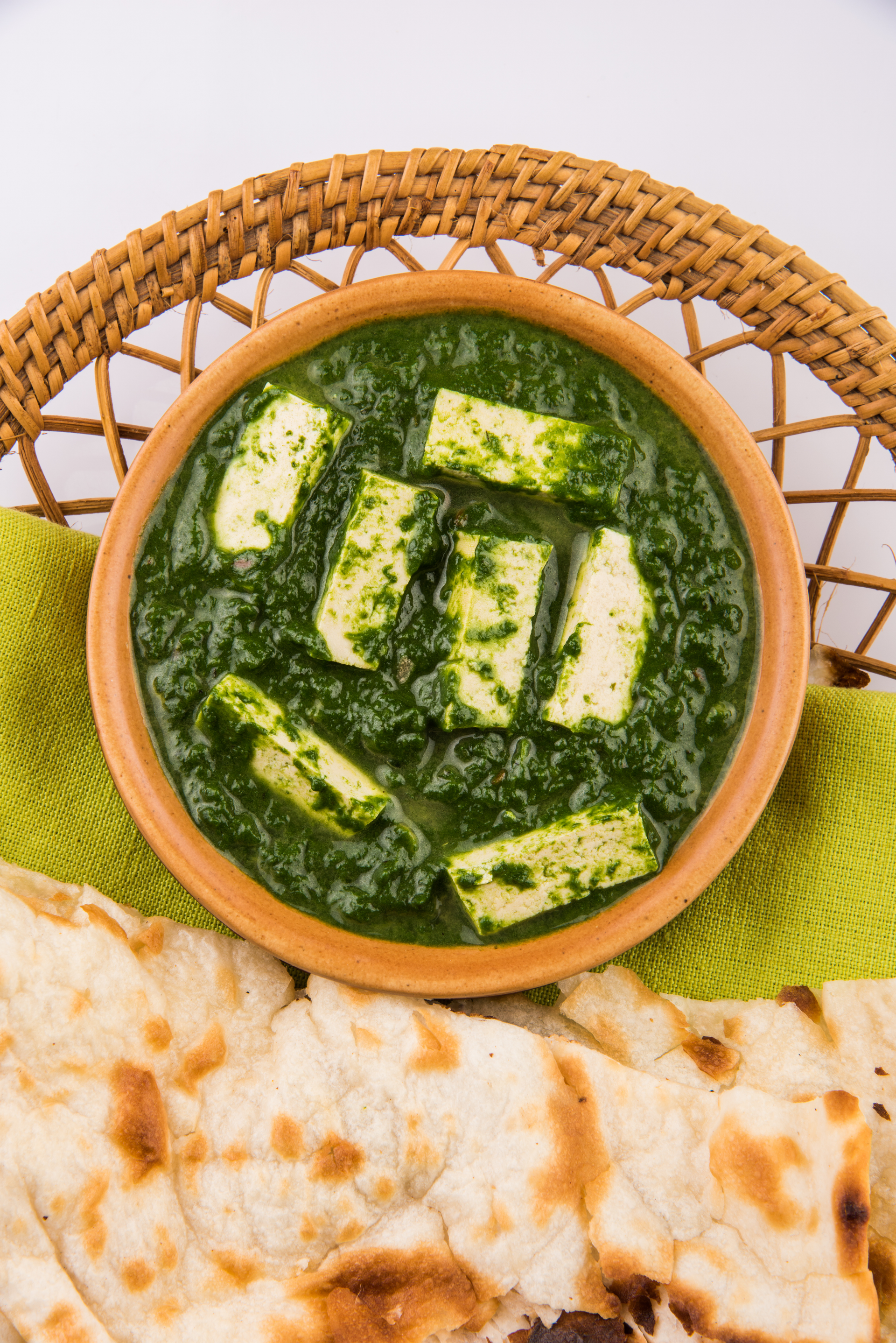 Overhead flat-lay of all ingredients for Punjabi Saag Paneer with Tandoori Roti laid out on a kitchen surface.