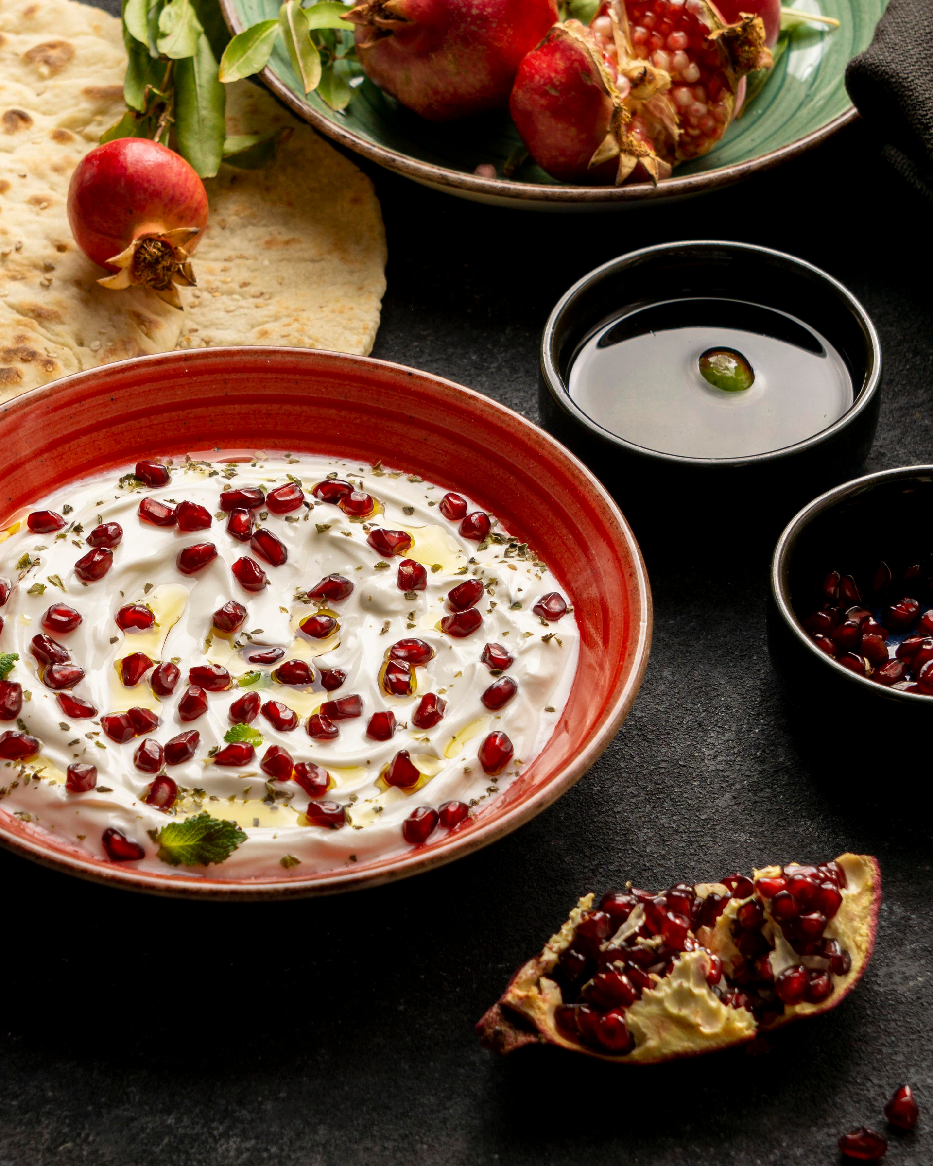Overhead flat-lay of all ingredients for Radiant Indian Raita with Pomegranate Seeds and Mint Leaves laid out on a kitchen surface.