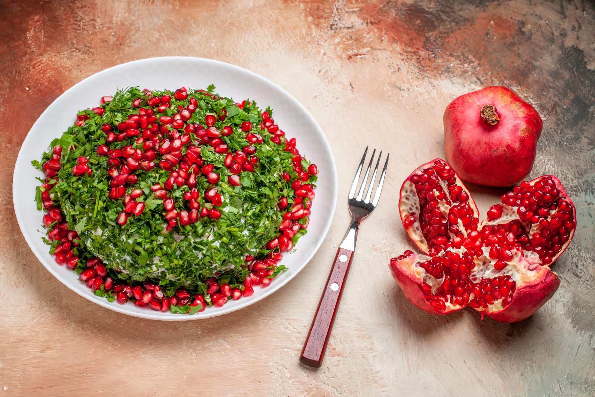 Overhead flat-lay of all ingredients for Refreshing Tunisian Minted Couscous with Pomegranate Reduction laid out on a kitchen surface.