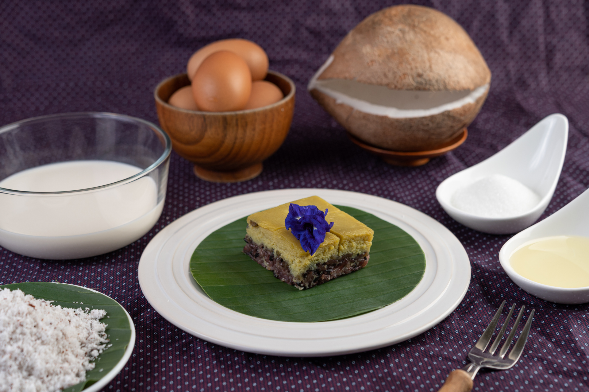 Overhead flat-lay of all ingredients for Rich Filipino Bibingka with Salted Egg and Grated Coconut laid out on a kitchen surface.