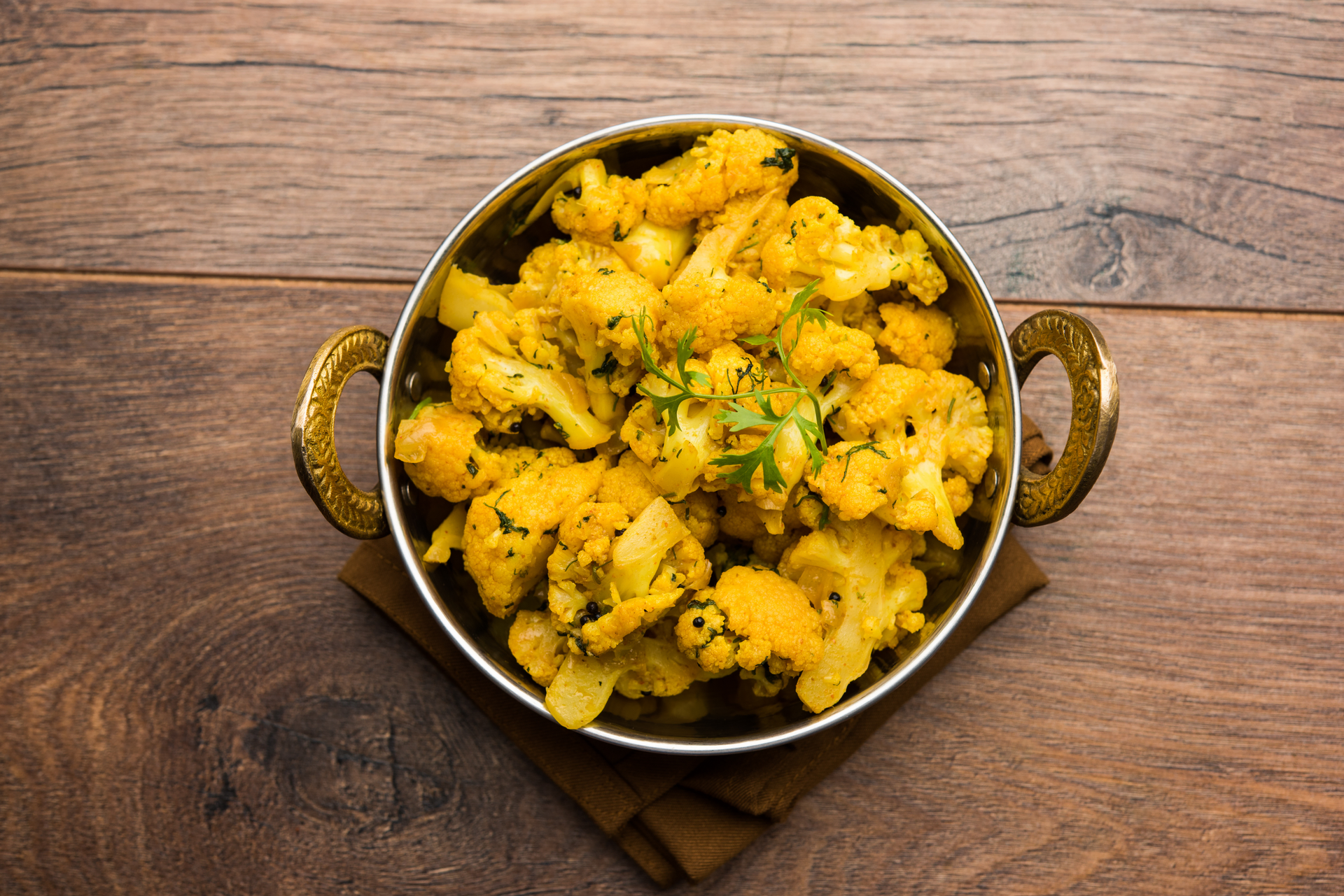 Overhead flat-lay of all ingredients for Rich Indian Aloo Gobi with Traditional Spices laid out on a kitchen surface.