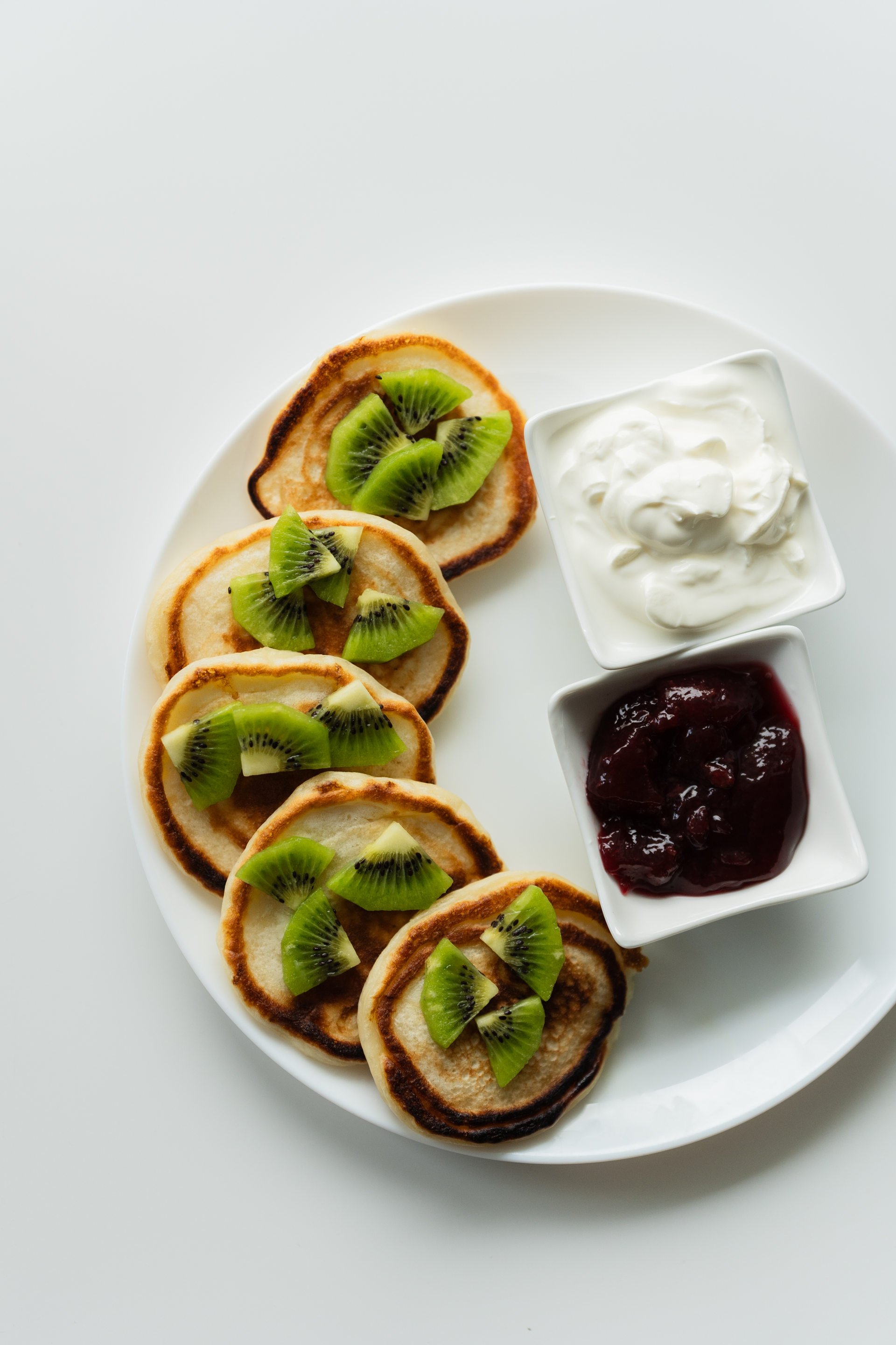 Overhead flat-lay of all ingredients for Russian Oladi with Sour Cream and Jam laid out on a kitchen surface.