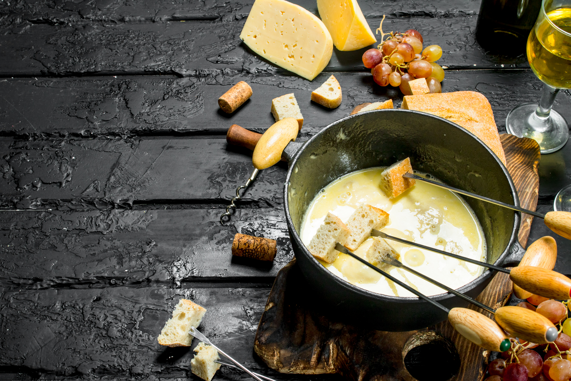 Overhead flat-lay of all ingredients for Rustic Alpine Raclette with Melted Cheese and Baby Potatoes laid out on a kitchen surface.