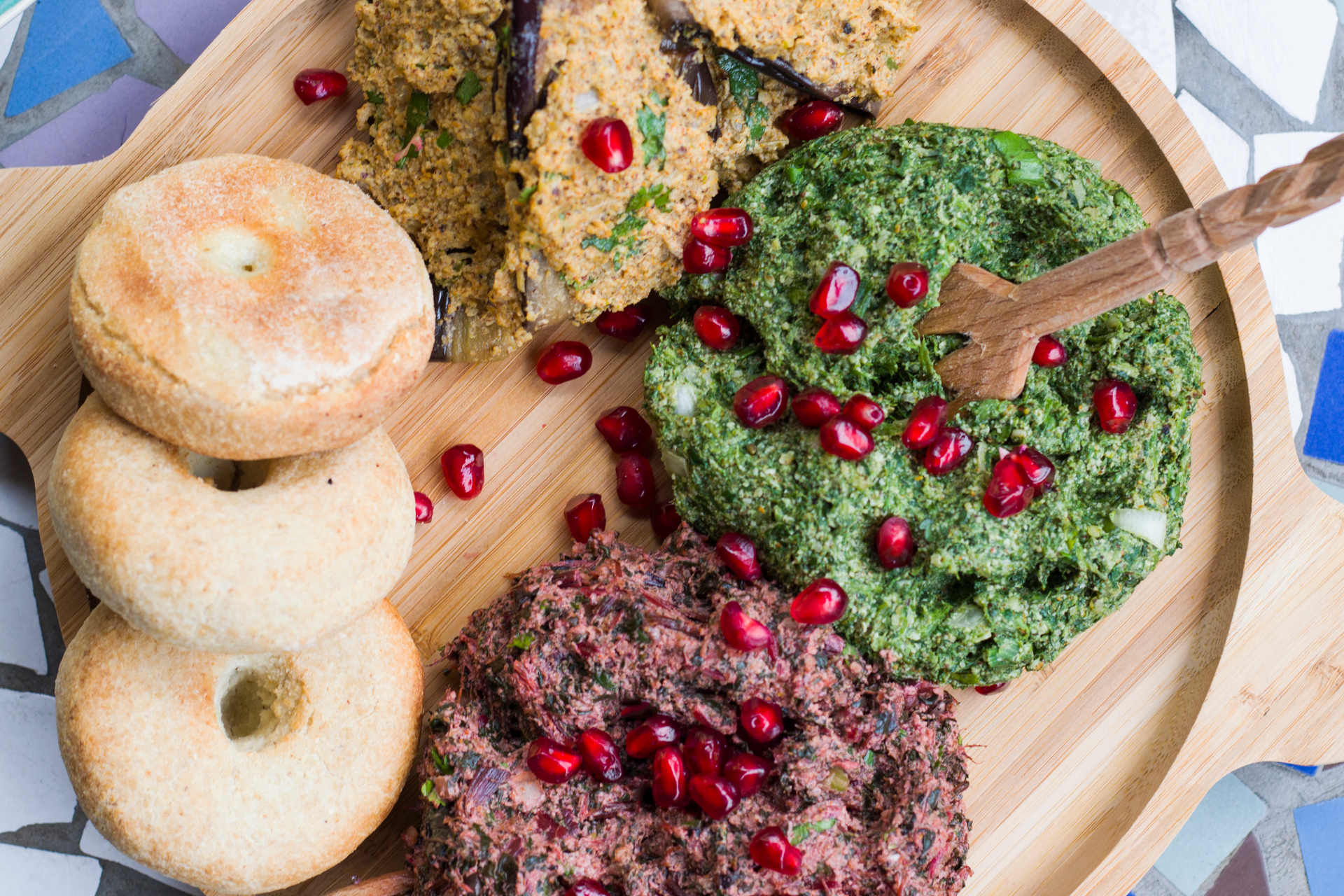 Overhead flat-lay of all ingredients for Rustic Georgian Spinach Pkhali with Walnuts and Pomegranate Seeds laid out on a kitchen surface.