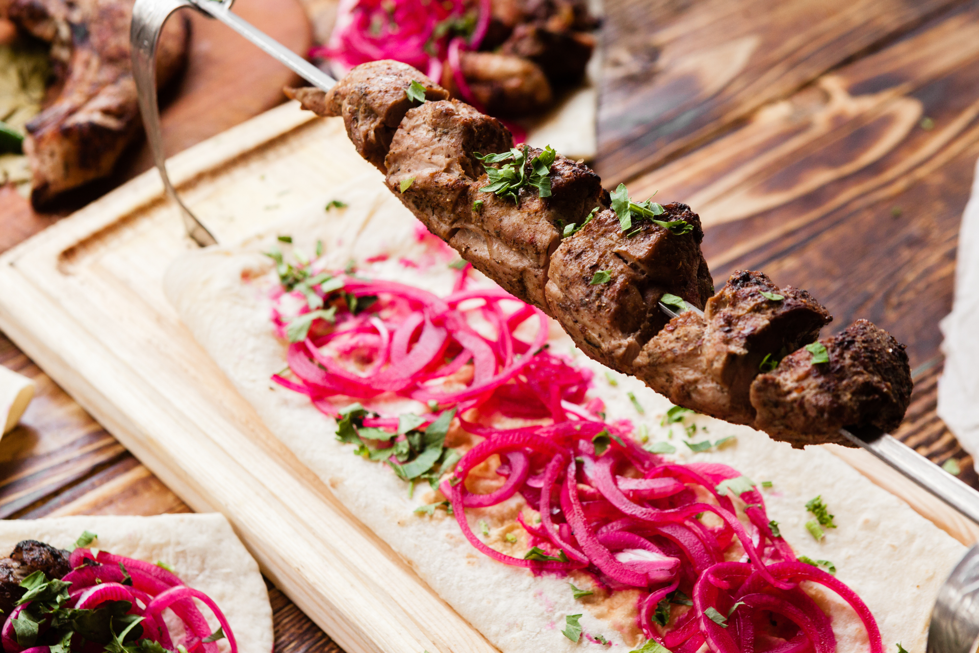 Overhead flat-lay of all ingredients for Saffron-Infused Persian Lamb Kebabs with Sumac Onions laid out on a kitchen surface.