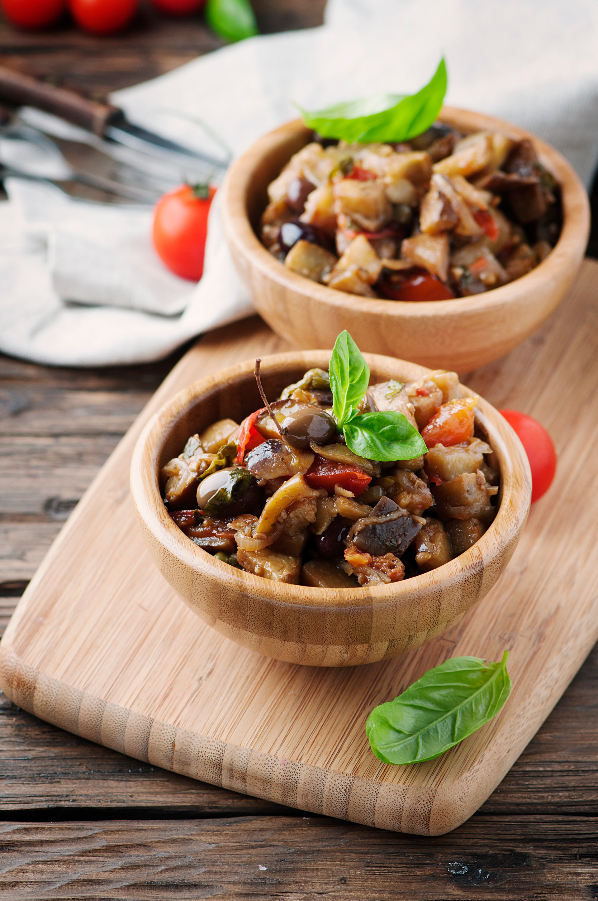 Overhead flat-lay of all ingredients for Savory Sicilian Caponata with Eggplant and Capers laid out on a kitchen surface.