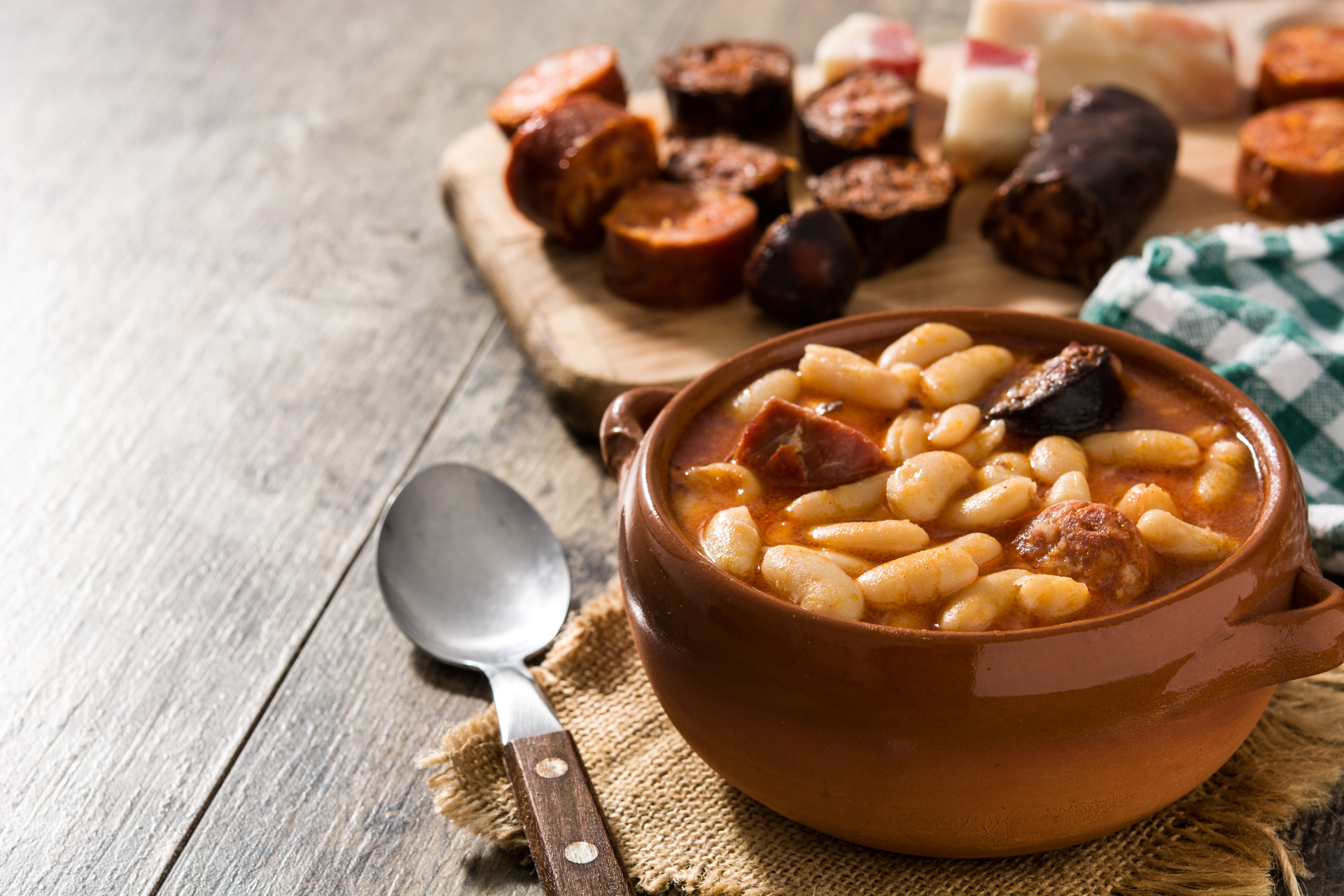 Overhead flat-lay of all ingredients for Savory Spanish Fabada Asturiana with Morcilla and Chorizo laid out on a kitchen surface.