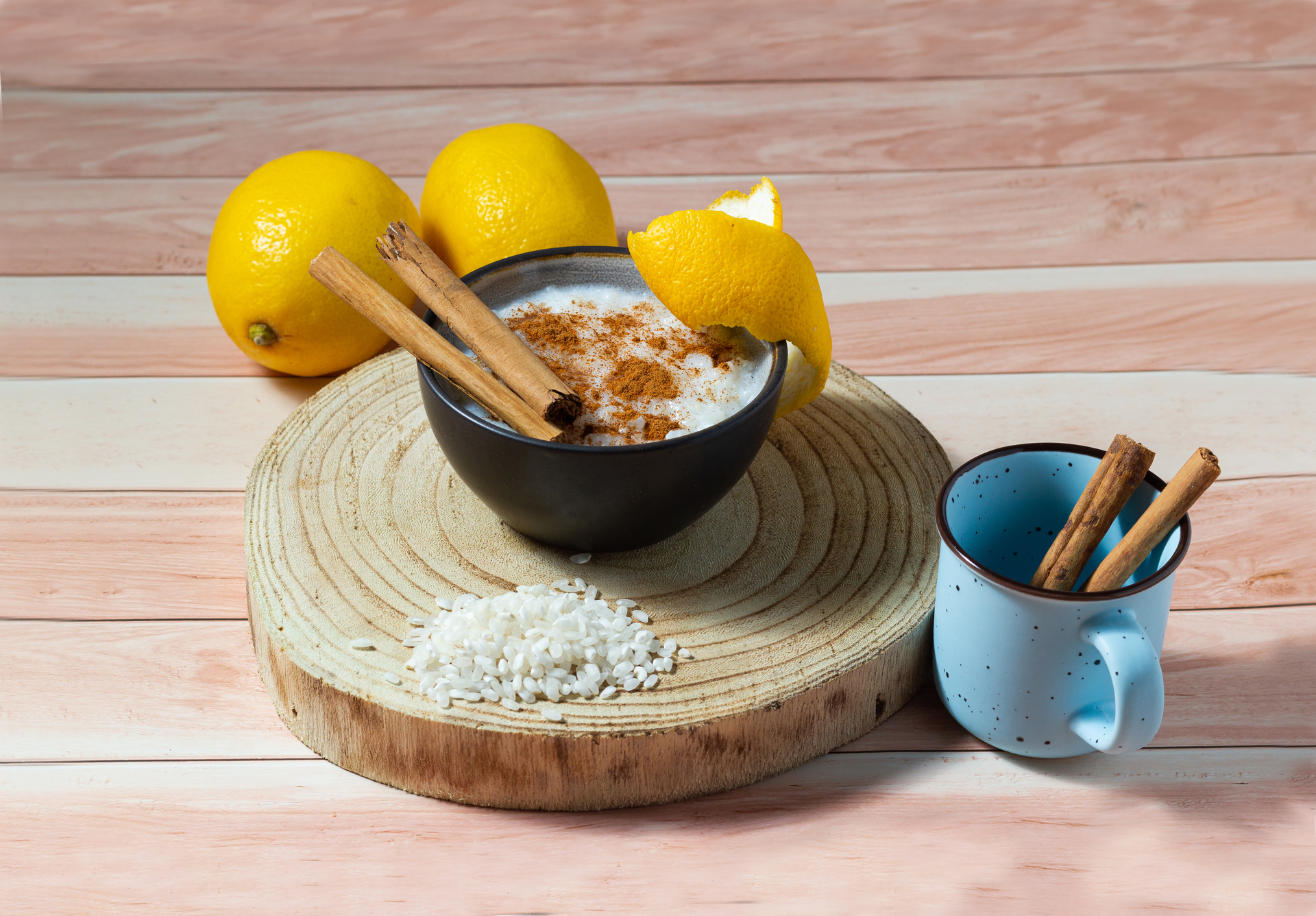 Overhead flat-lay of all ingredients for Silken Portuguese Arroz Doce with Cinnamon and Lemon Zest laid out on a kitchen surface.
