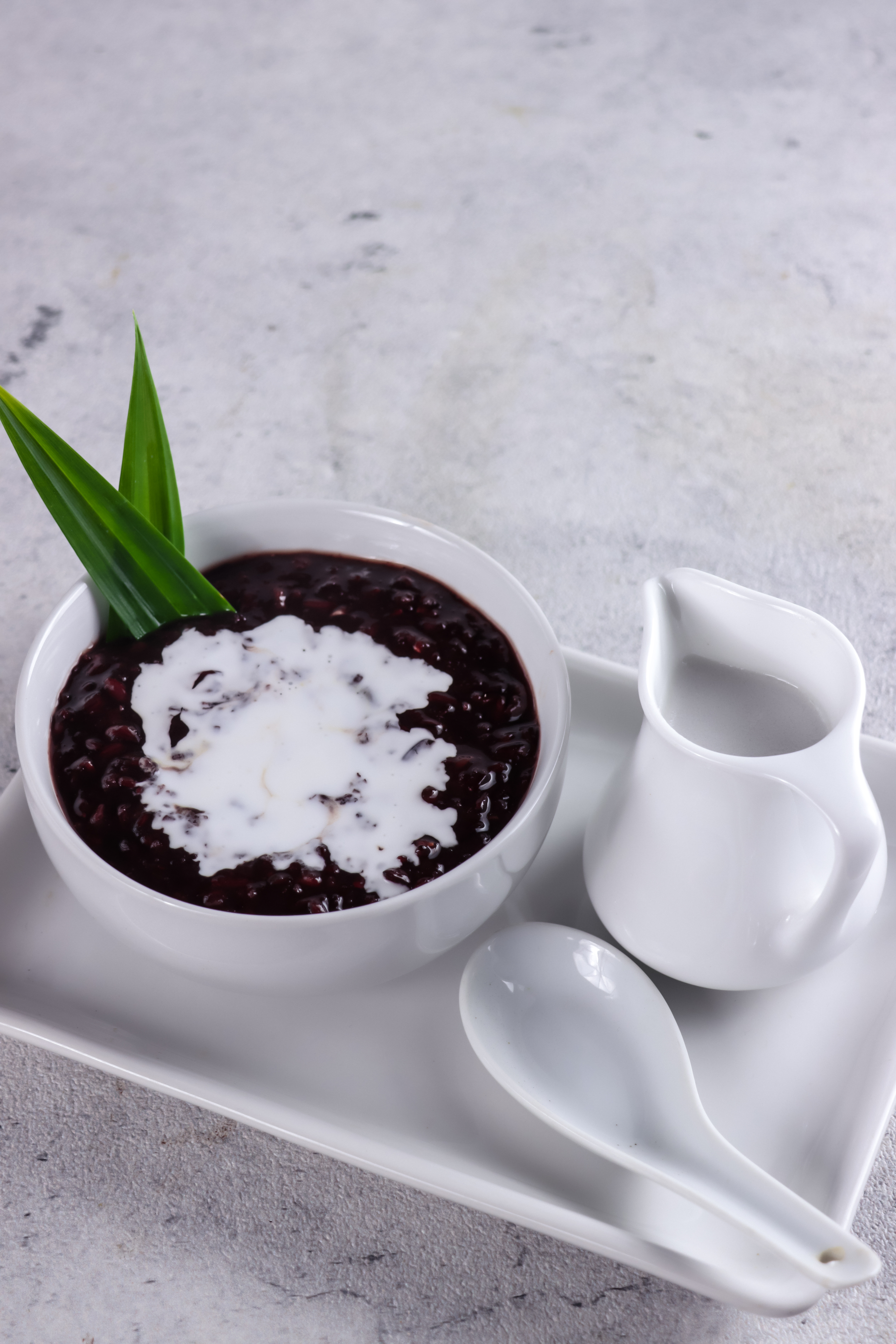 Overhead flat-lay of all ingredients for Silky Indonesian Bubur Ketan Hitam with Coconut Milk laid out on a kitchen surface.