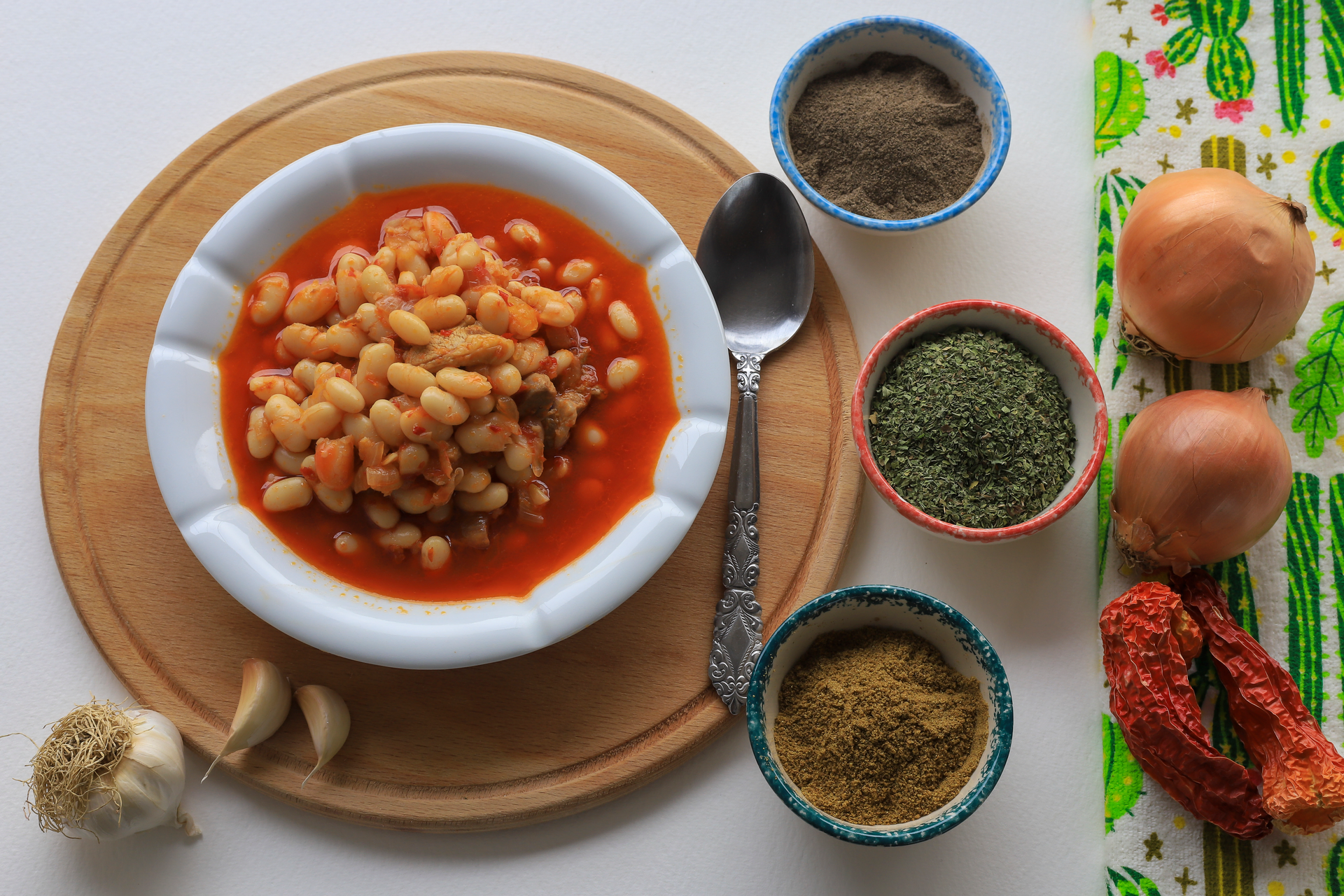 Overhead flat-lay of all ingredients for Smoky Algerian Loubia with Cumin and Chili Oil laid out on a kitchen surface.
