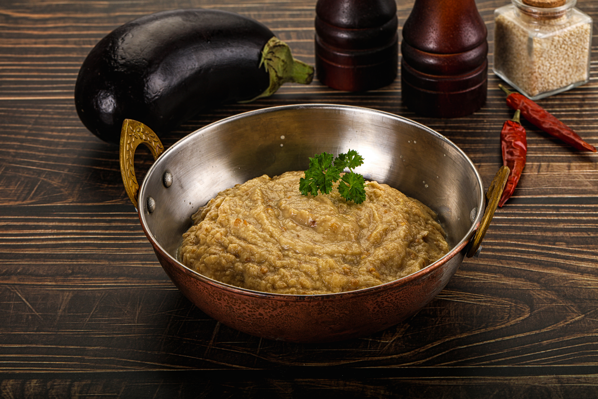 Overhead flat-lay of all ingredients for Smoky Middle Eastern Eggplant Mash with Tahini Drizzle laid out on a kitchen surface.
