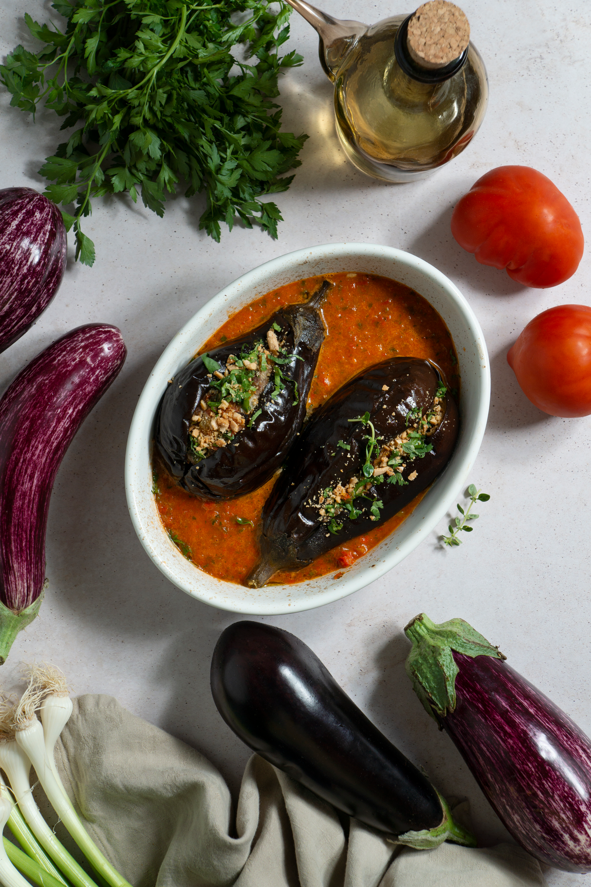 Overhead flat-lay of all ingredients for Smoky Moroccan Eggplant Zaalouk with Harissa Drizzle laid out on a kitchen surface.
