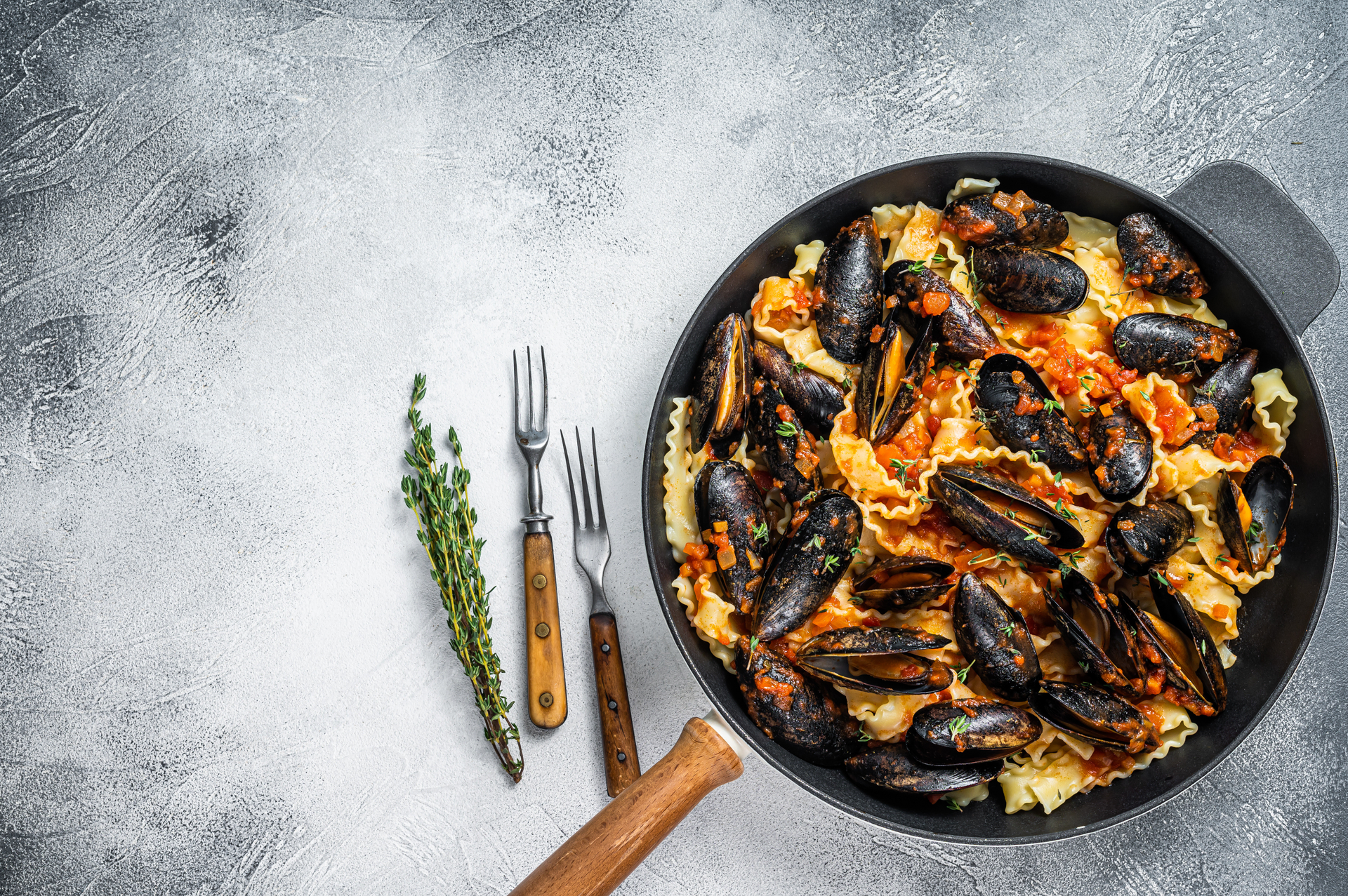 Overhead flat-lay of all ingredients for Smoky Spanish Paella with Rabbit and Snails laid out on a kitchen surface.