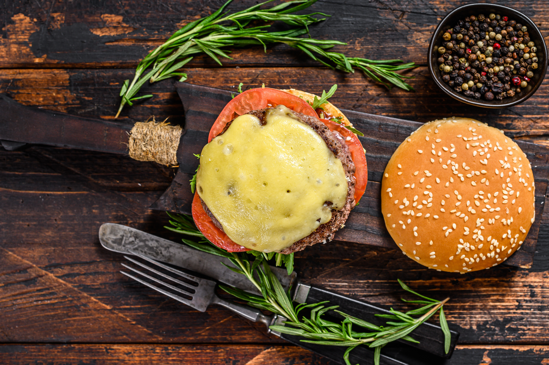 Overhead flat-lay of all ingredients for Smoky Swiss Raclette Burger with Alpine Herb Relish laid out on a kitchen surface.