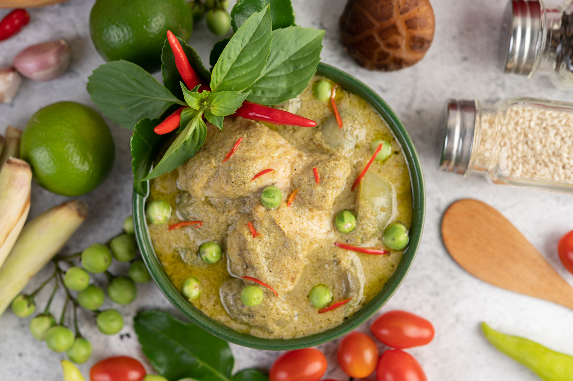 Overhead flat-lay of all ingredients for Southeast Asian Tamarind Chicken in Banana Leaf with Mint Chutney laid out on a kitchen surface.