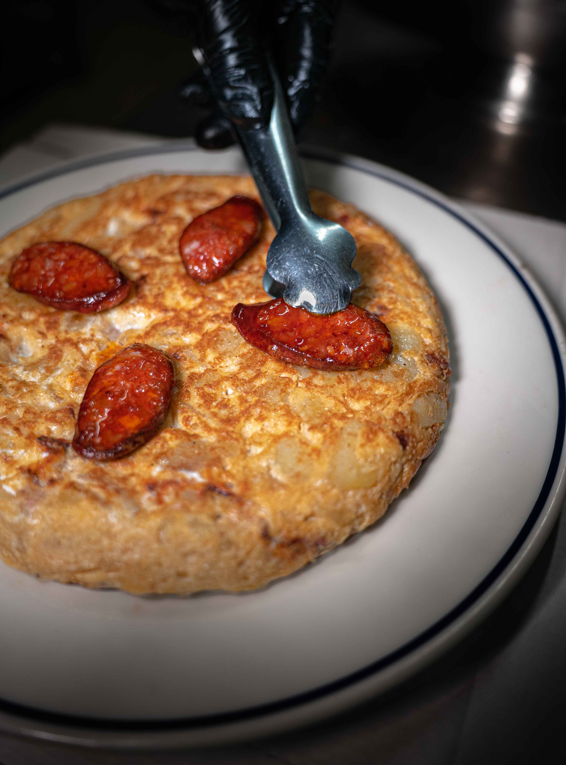 Overhead flat-lay of all ingredients for Spanish Tortilla Española with Chorizo laid out on a kitchen surface.