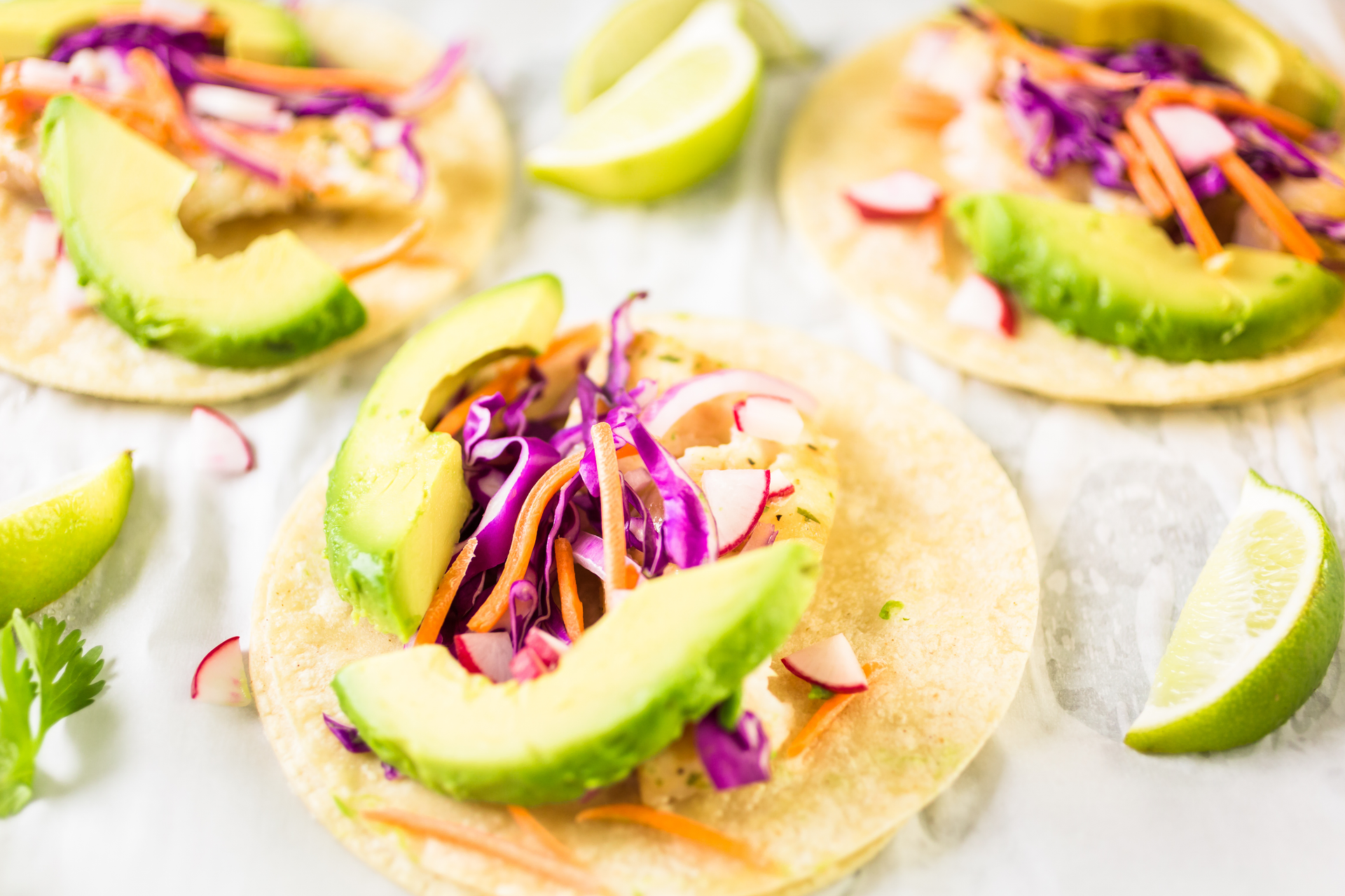 Overhead flat-lay of all ingredients for Spicy Caribbean Jerk Jackfruit Tacos with Avocado Cream laid out on a kitchen surface.
