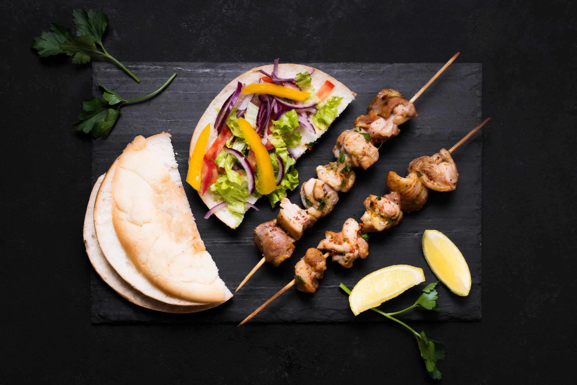 Overhead flat-lay of all ingredients for Spicy Greek Lamb Souvlaki laid out on a kitchen surface.