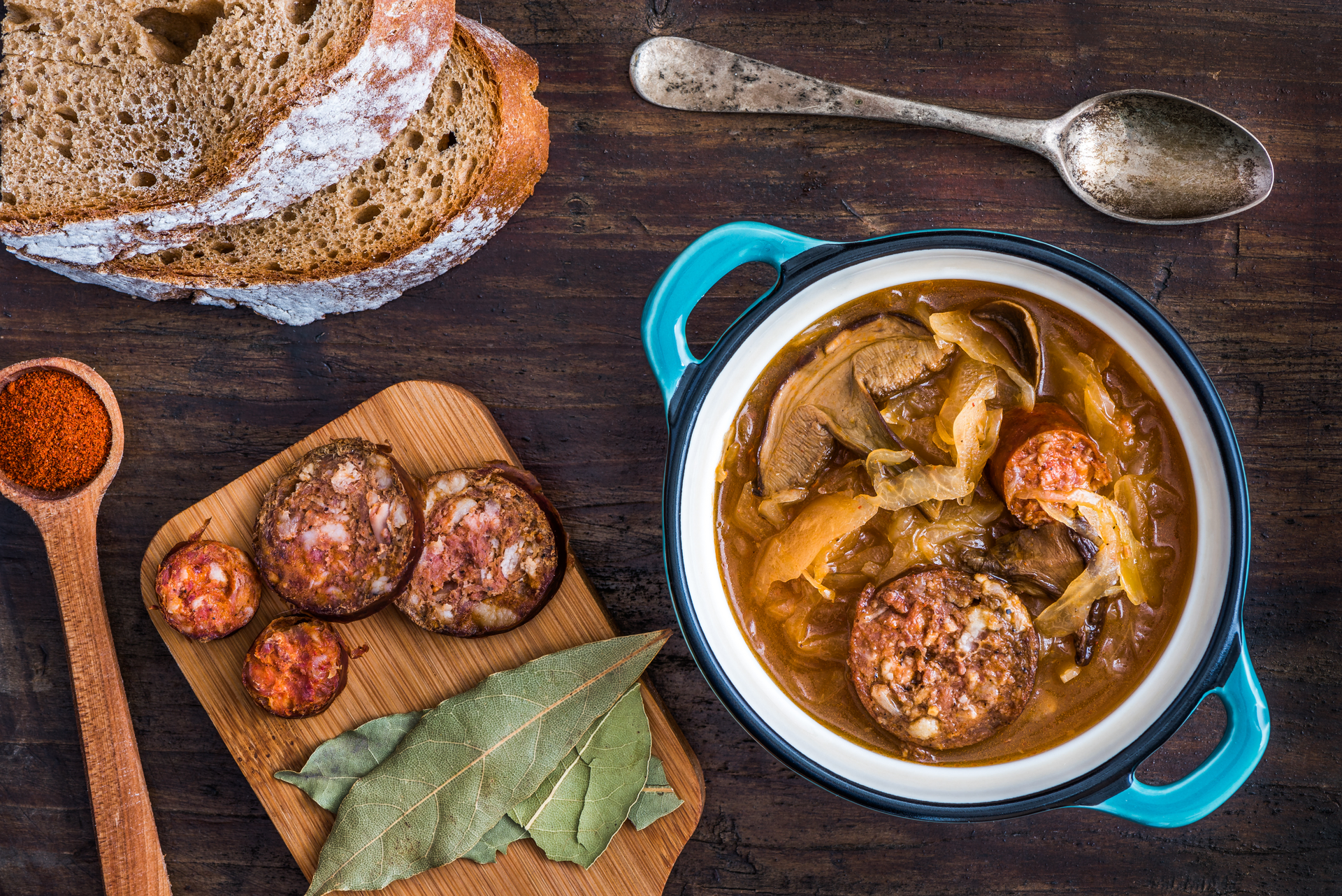 Overhead flat-lay of all ingredients for Spicy Hungarian Debrecener Sausage Stew laid out on a kitchen surface.