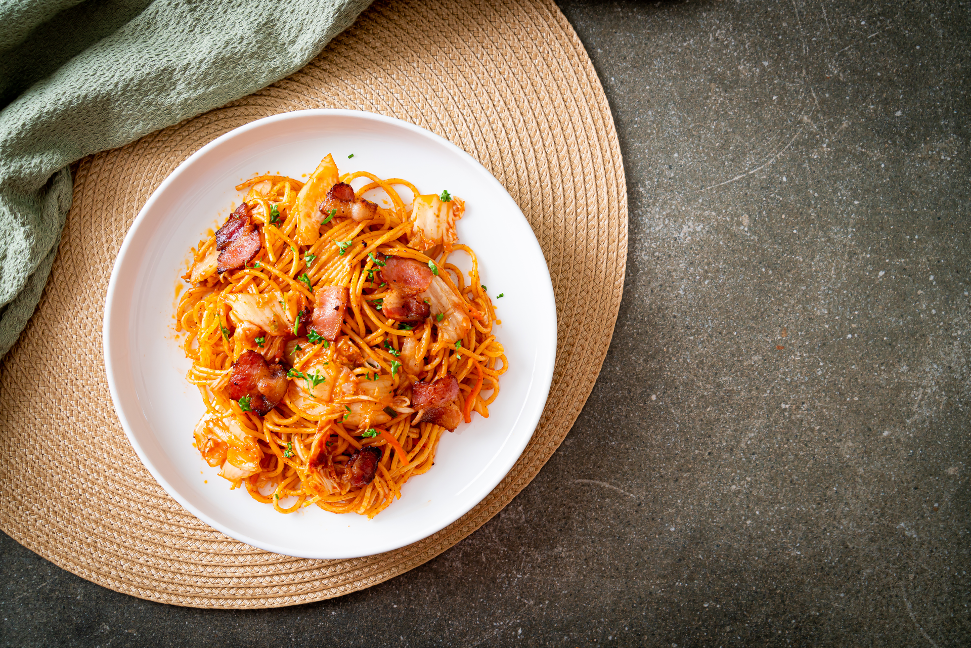 Overhead flat-lay of all ingredients for Spicy Korean Kimchi Carbonara with Perilla Leaves laid out on a kitchen surface.