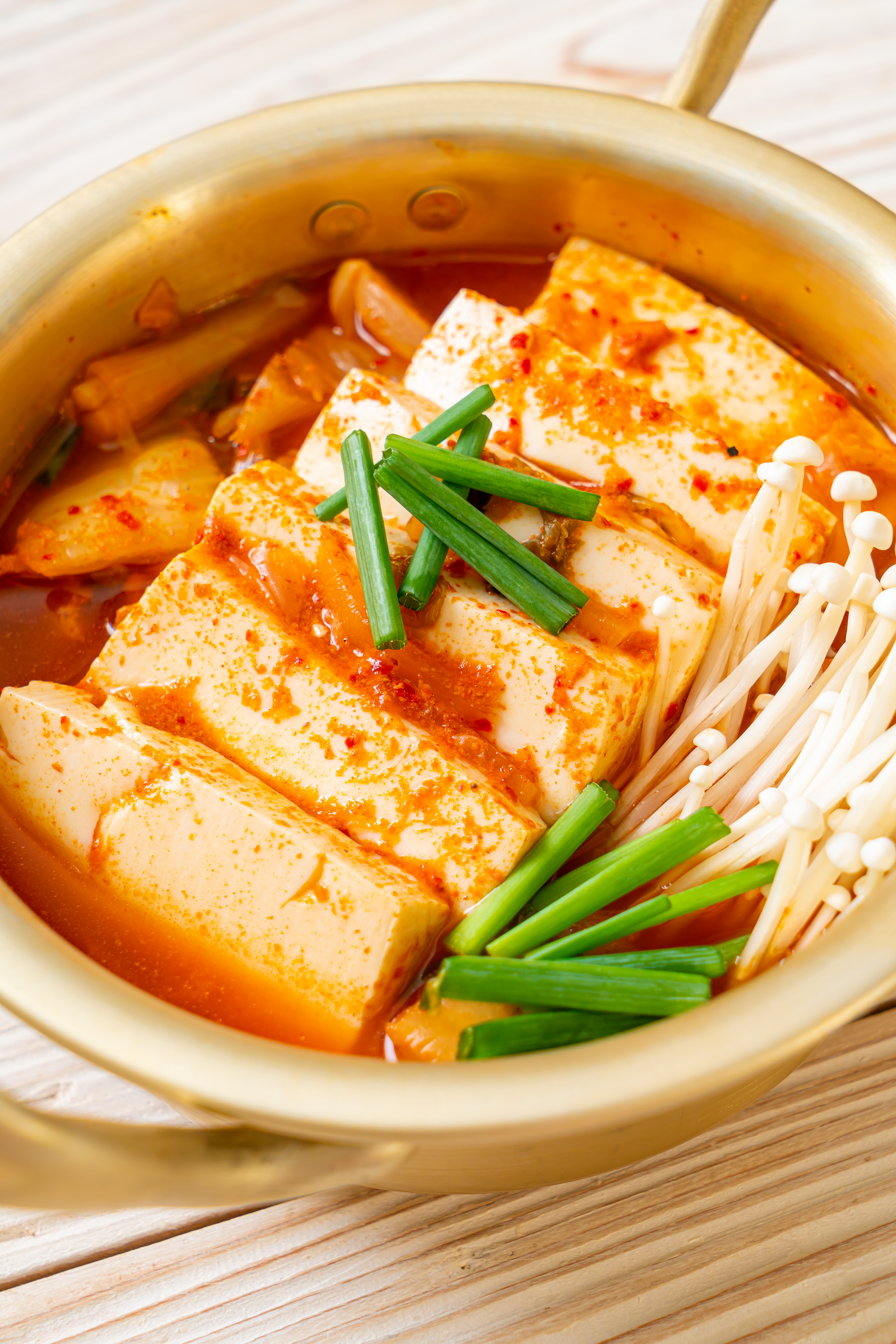 Overhead flat-lay of all ingredients for Spicy Korean Kimchi Jjigae with Tofu laid out on a kitchen surface.