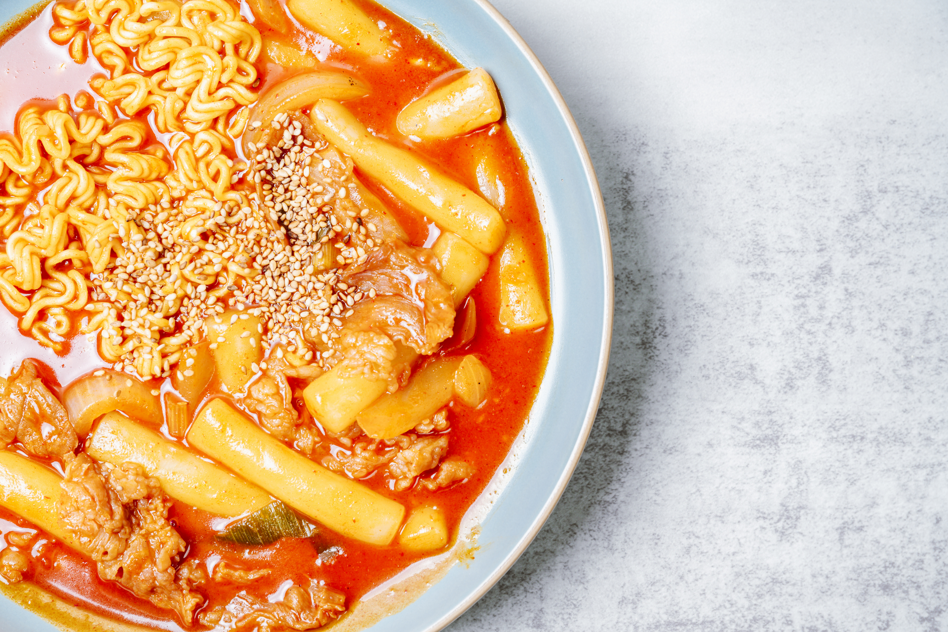 Overhead flat-lay of all ingredients for Spicy Korean Tteokbokki with Cheese and Kimchi laid out on a kitchen surface.