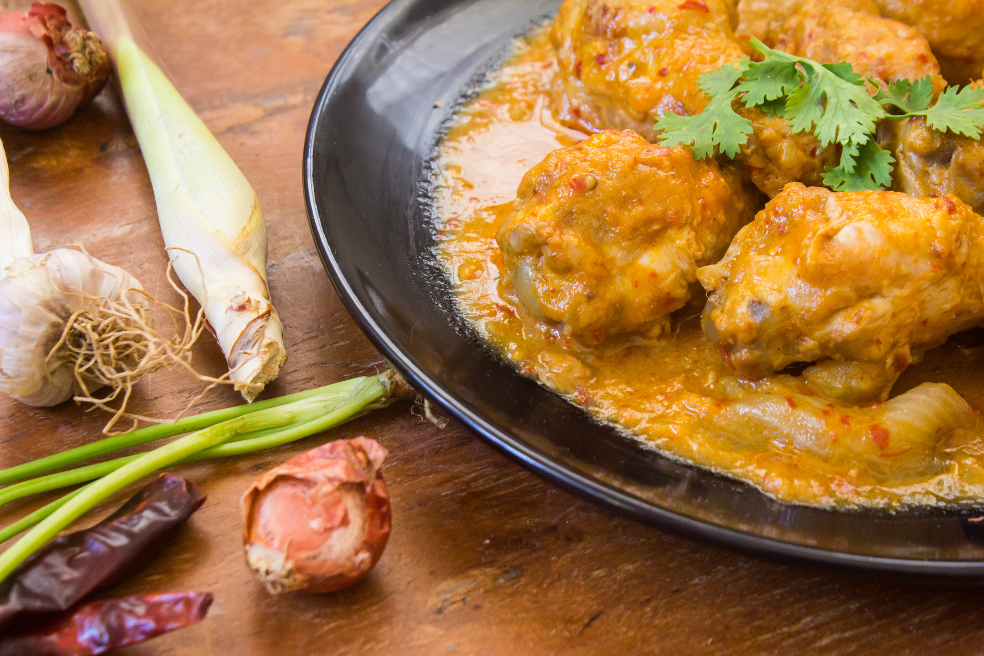 Overhead flat-lay of all ingredients for Spicy Malaysian Ayam Percik with Lemongrass and Turmeric laid out on a kitchen surface.