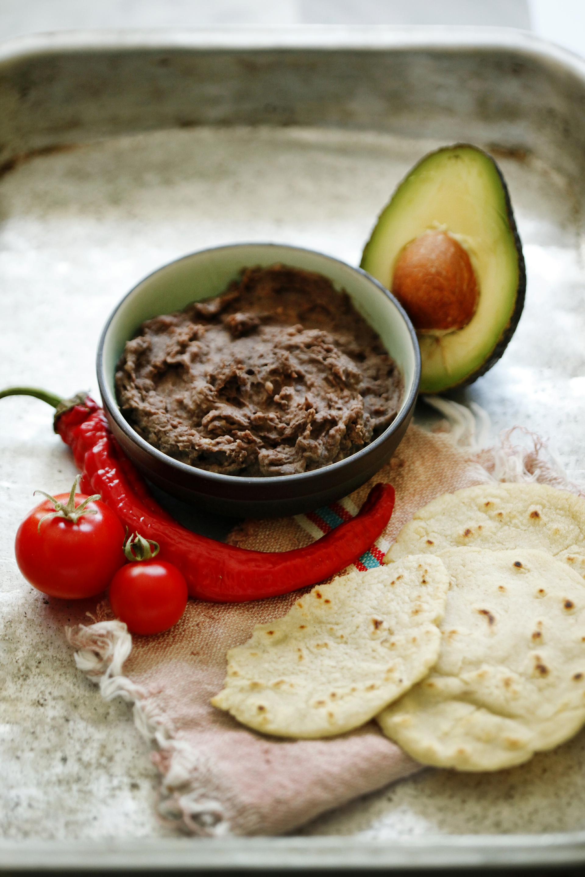 Overhead flat-lay of all ingredients for Spicy Mexican Huaraches with Black Bean Purée laid out on a kitchen surface.
