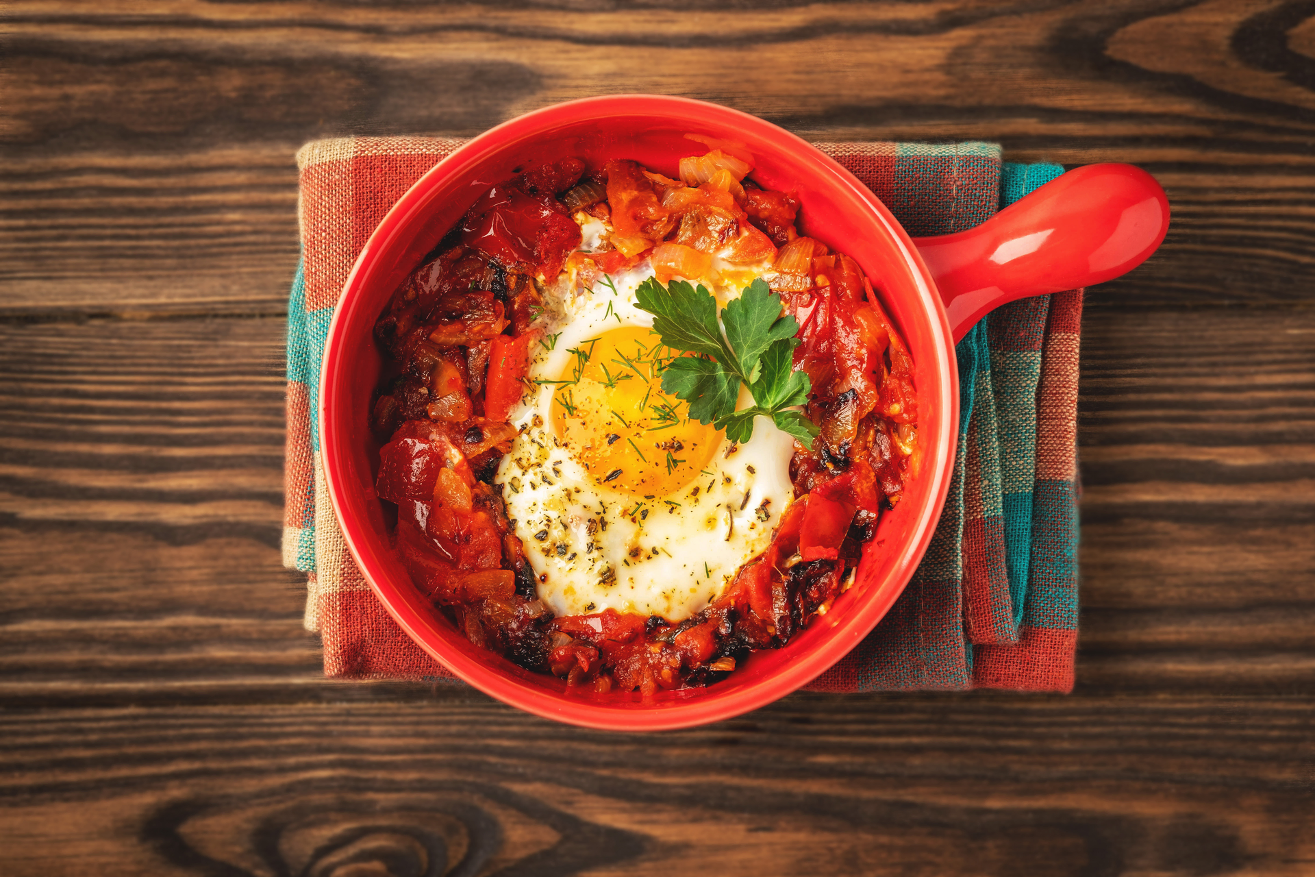 Overhead flat-lay of all ingredients for Spicy Tunisian Chakchouka with Harissa and Eggs laid out on a kitchen surface.